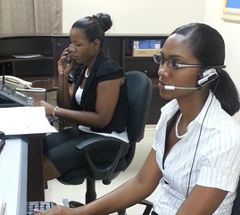 Two women wearing headsets working at desks in an office.