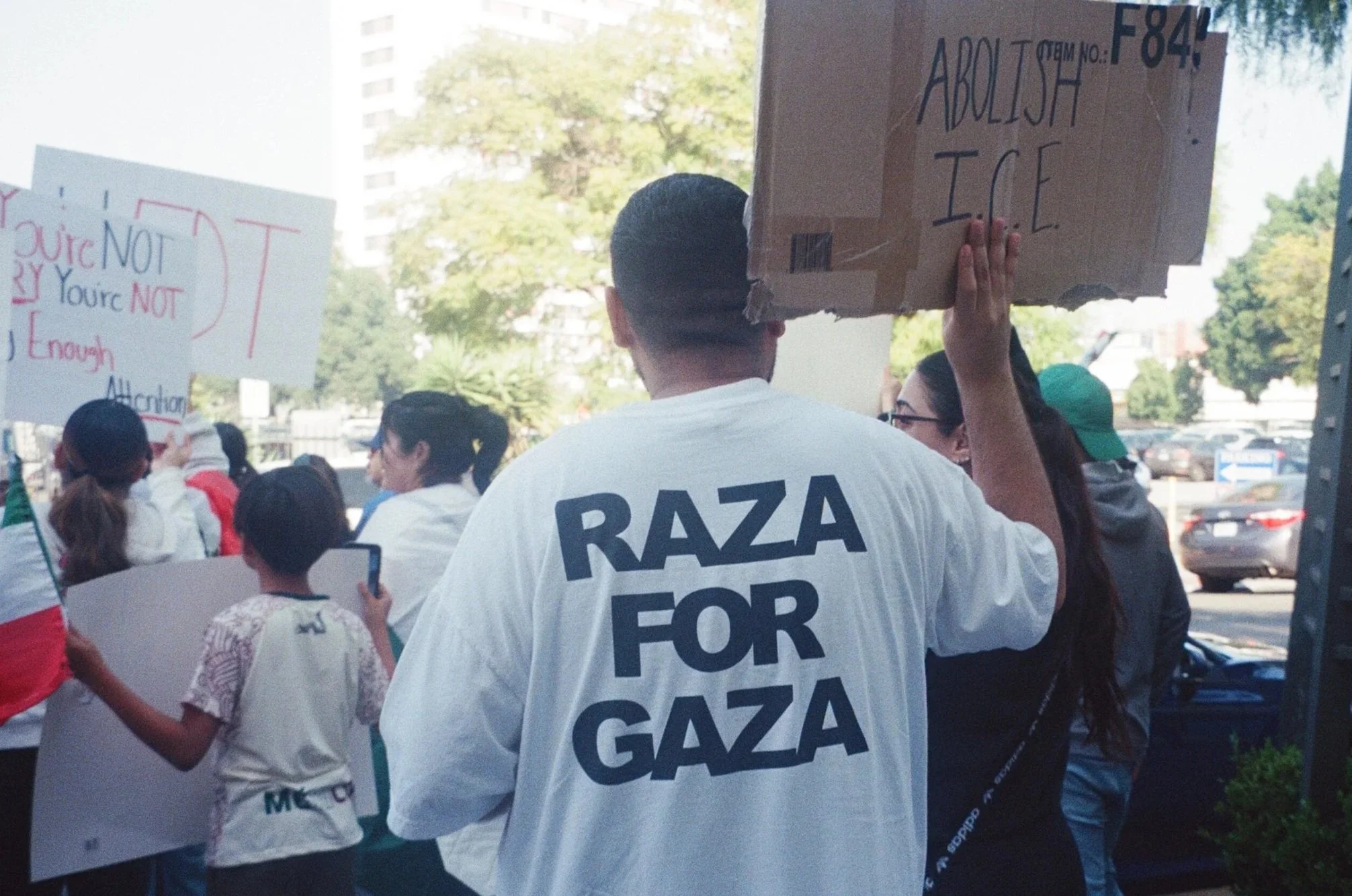 "Raza for Gaza" t-shirt, "Abolish ICE" signage held by protester in LA. '25