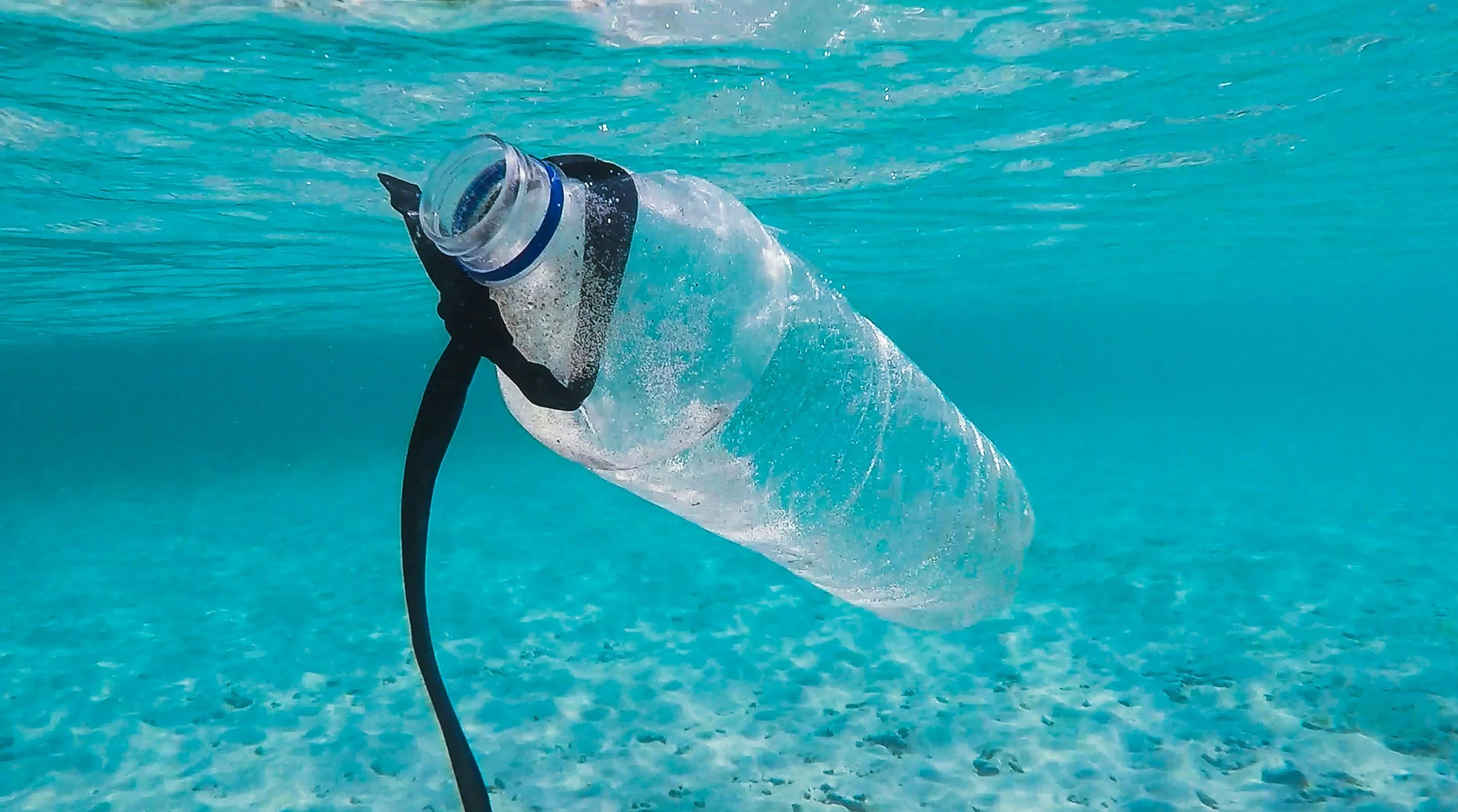 A close up of a clear plastic bottle submerged in the blue waters of the ocean.