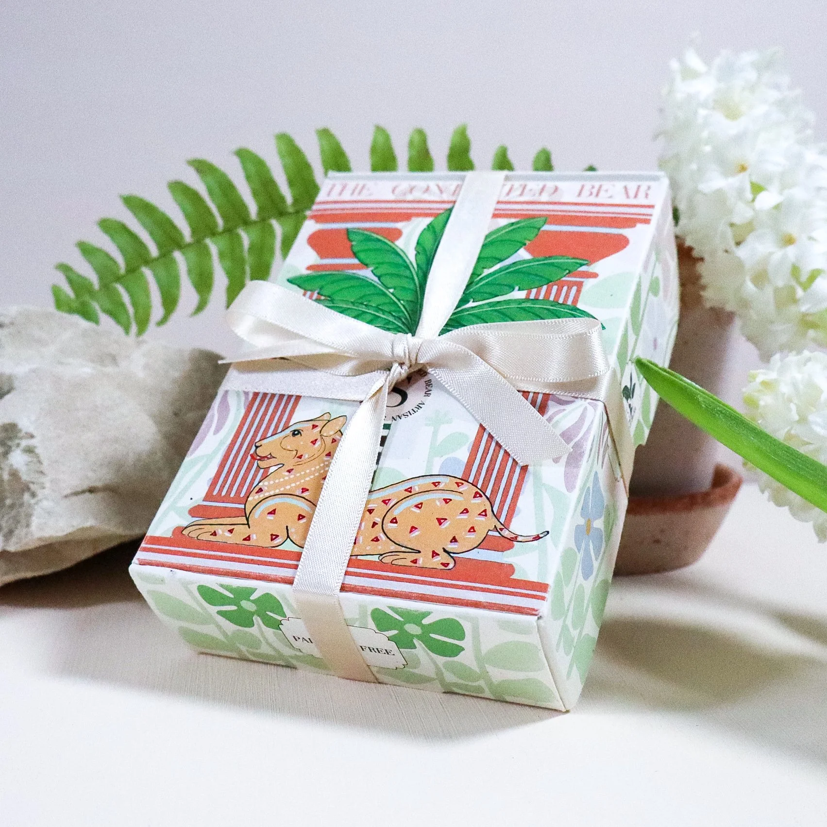 A side view of a beautiful, recycled, illustrated soap box leaning on a stone surrounded by ribbon and ivy.