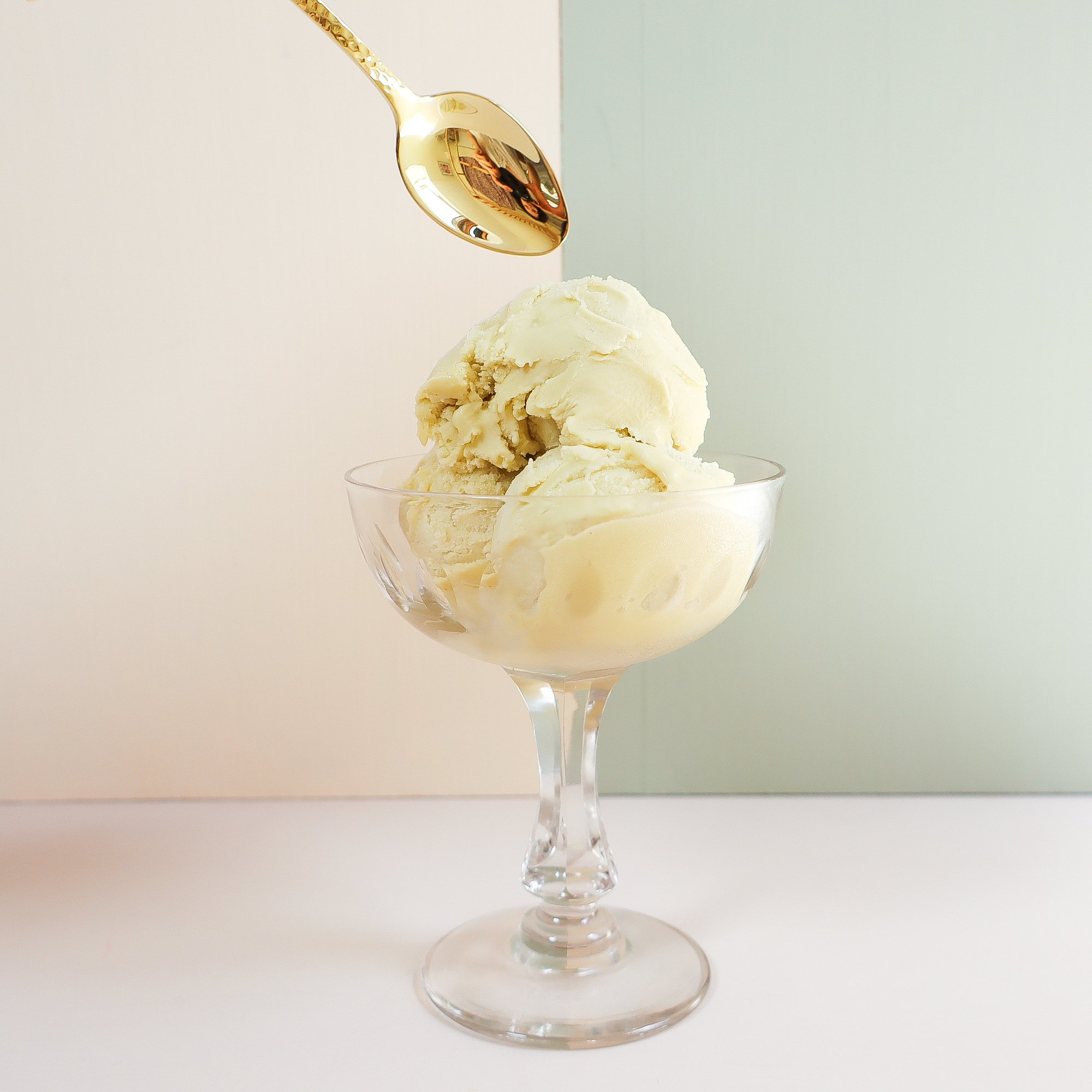 Arthur Price Golden teaspoon diving into a vintage glass full of pistachio ice cream.