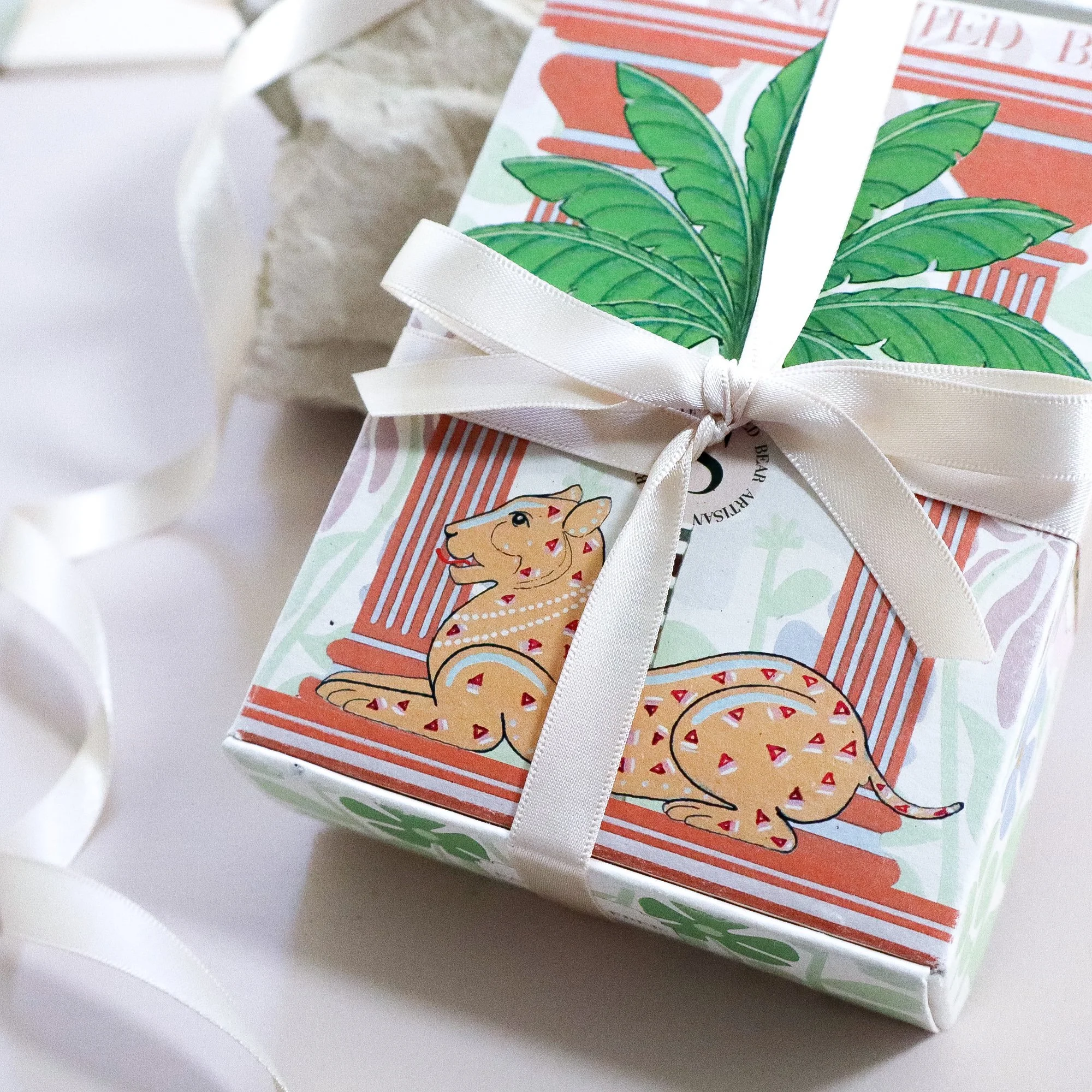 A close up photo of a hand illustrated soap box wrapped in ivory recycled plastic bottle ribbon. Ivory ribbon cascades everywhere in the photo.