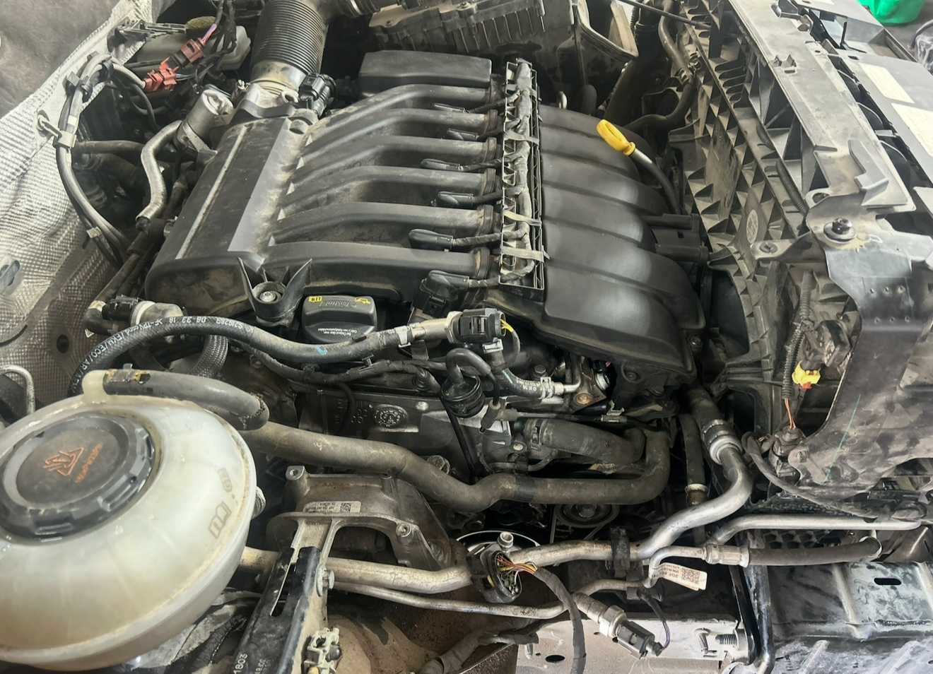 Car engine with visible intake manifold and various hoses and components.