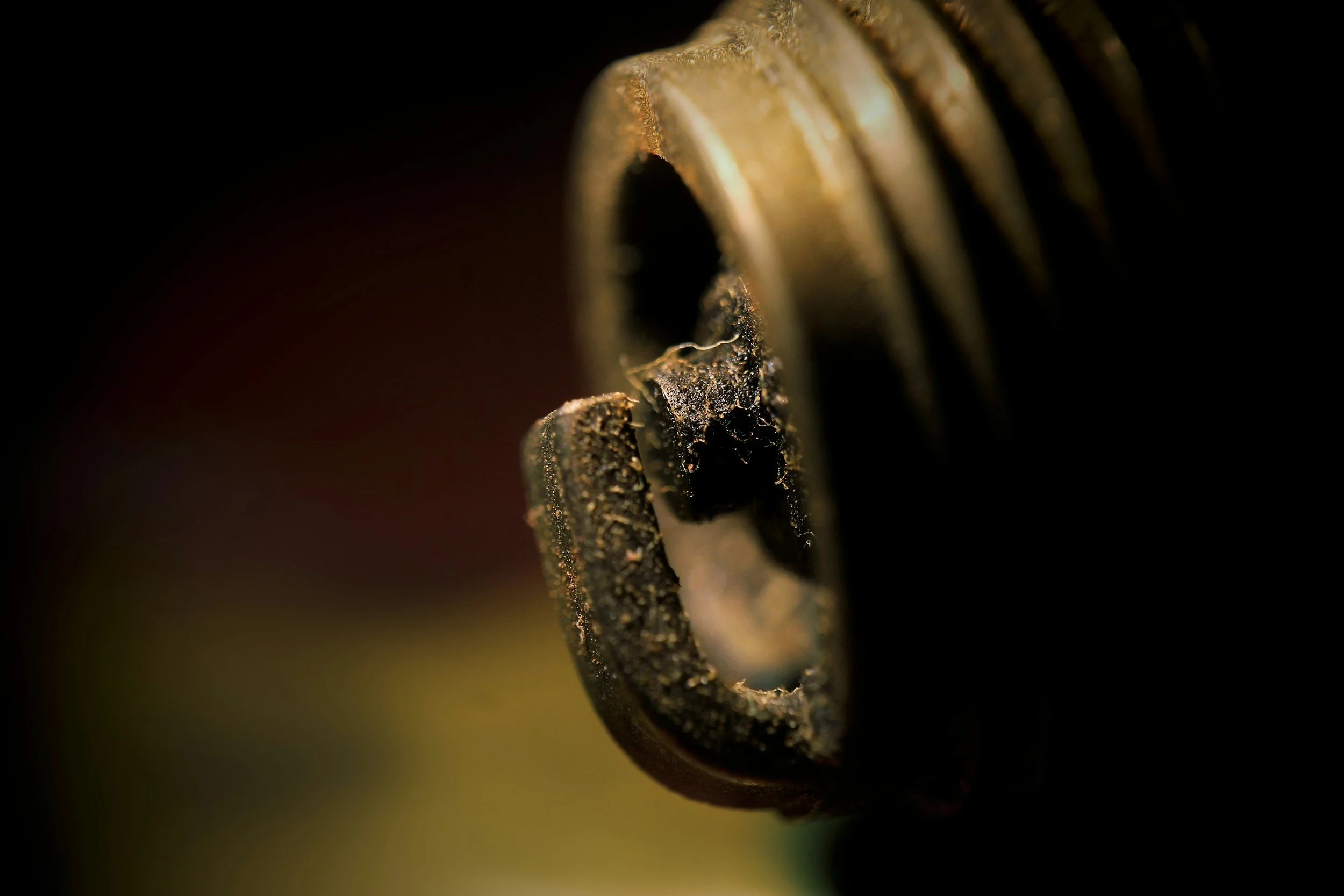 Close-up of a weathered metal screw head with dust and dirt, against a dark background.