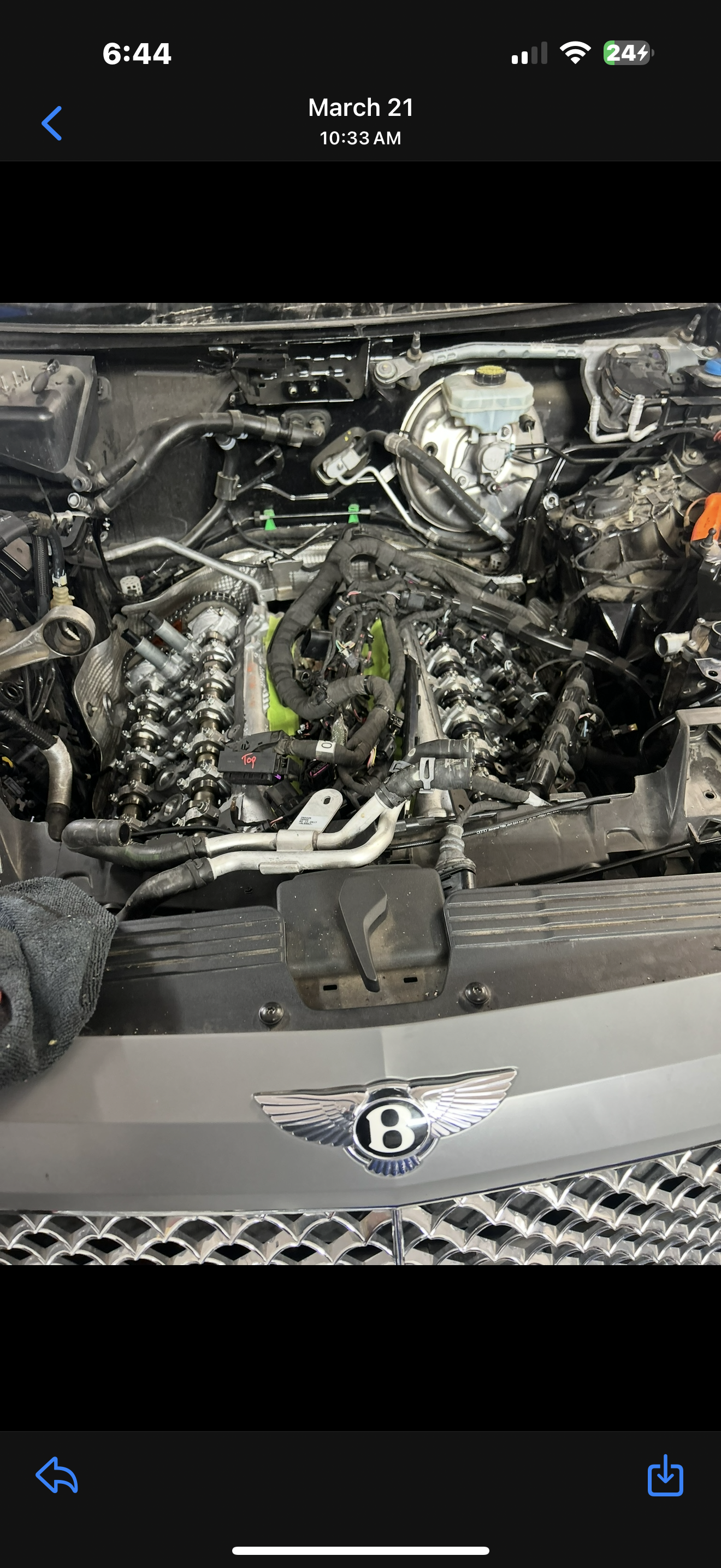 Engine of a luxury Bentley car with its hood open, revealing the engine components.