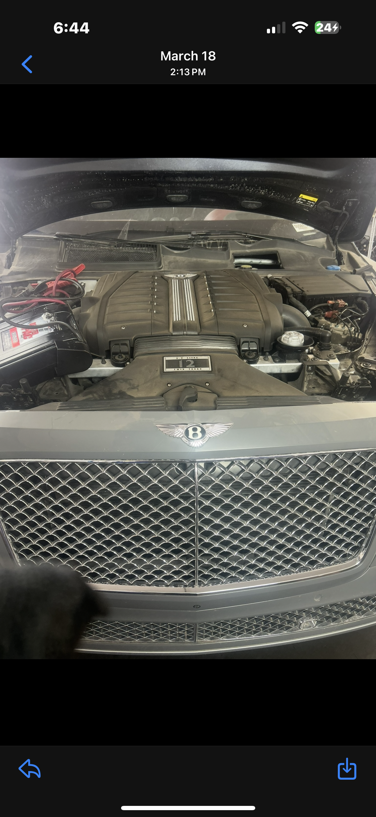 Under the hood of a Bentley car, showing the engine and front grille.
