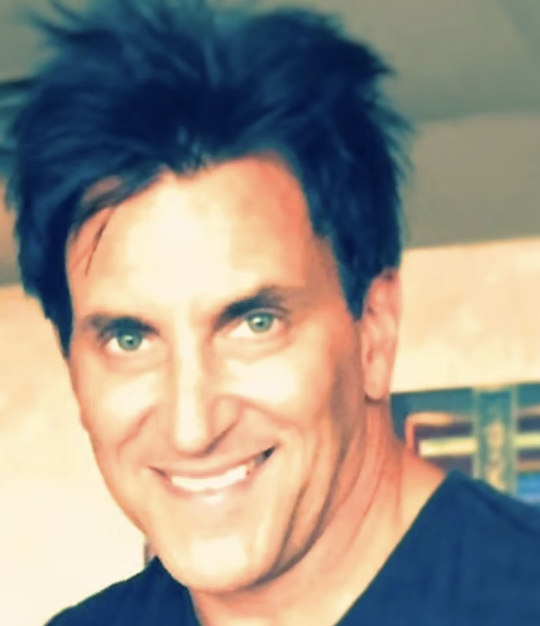 Portrait of a smiling man with dark hair and green eyes