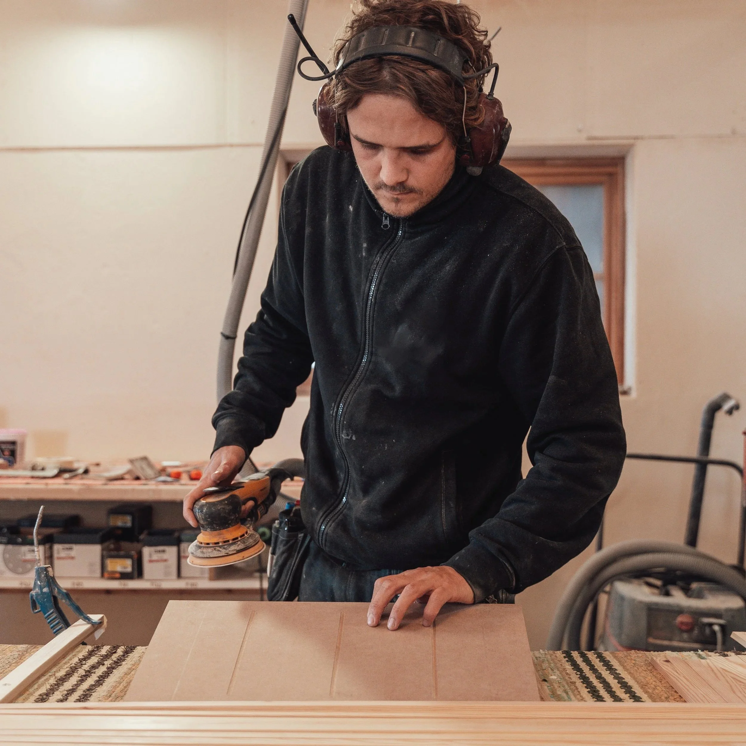 En man som arbetar med slipmaskin i ett verkstadsrum.