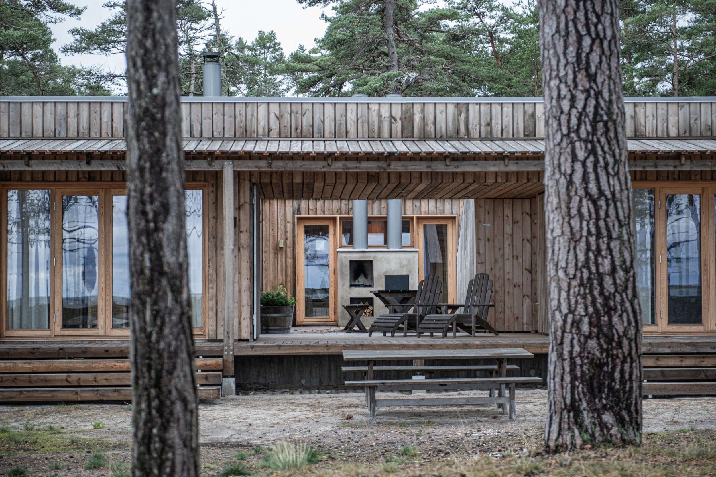 Trähus med stor bakgård, utomhusgrill och utomhusmöbler, omgiven av träd