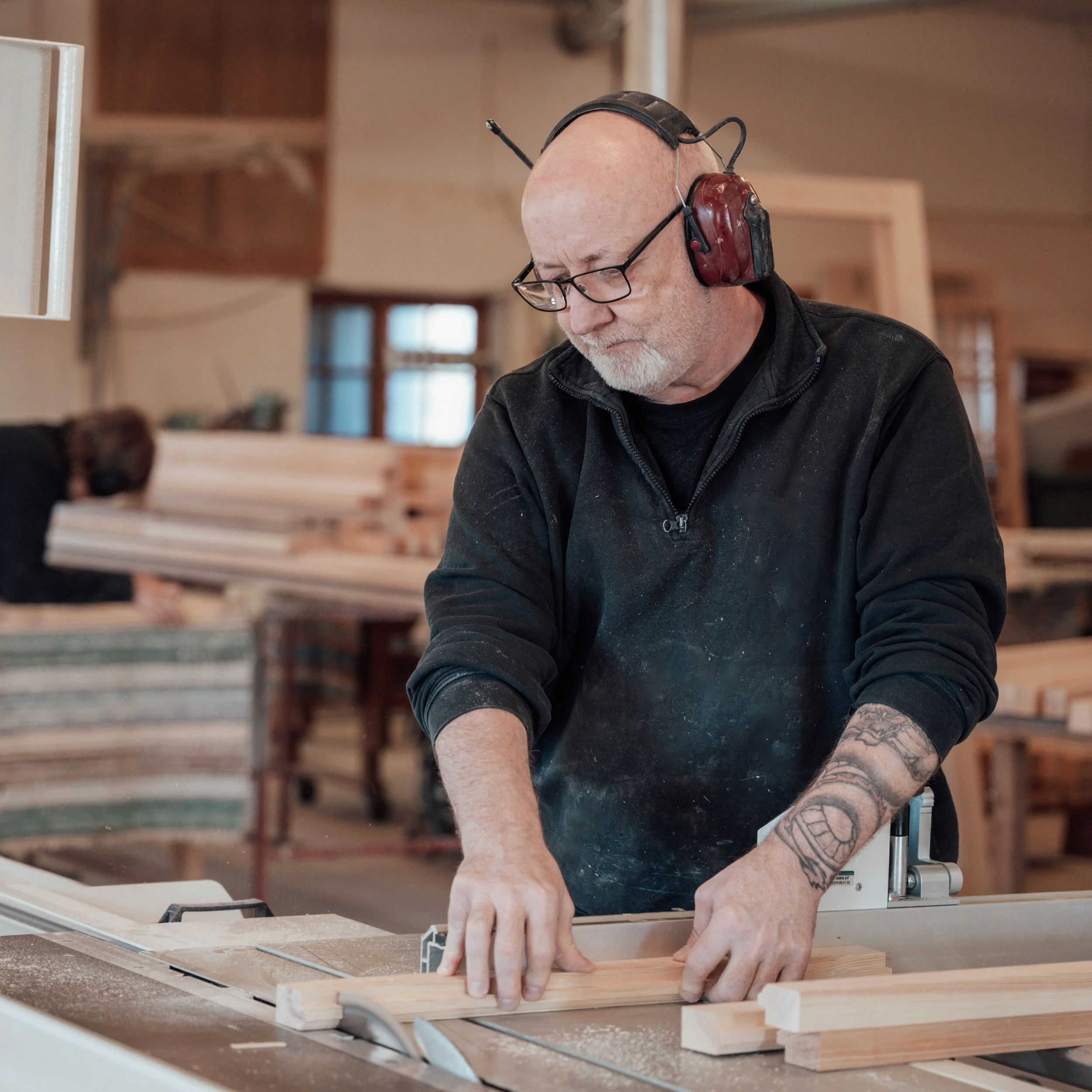 Man arbetar med trä i ett snickeri, han använder en plywoodskiva på ett arbetsbord, avsiktligt för att göra ett snickeriarbete.