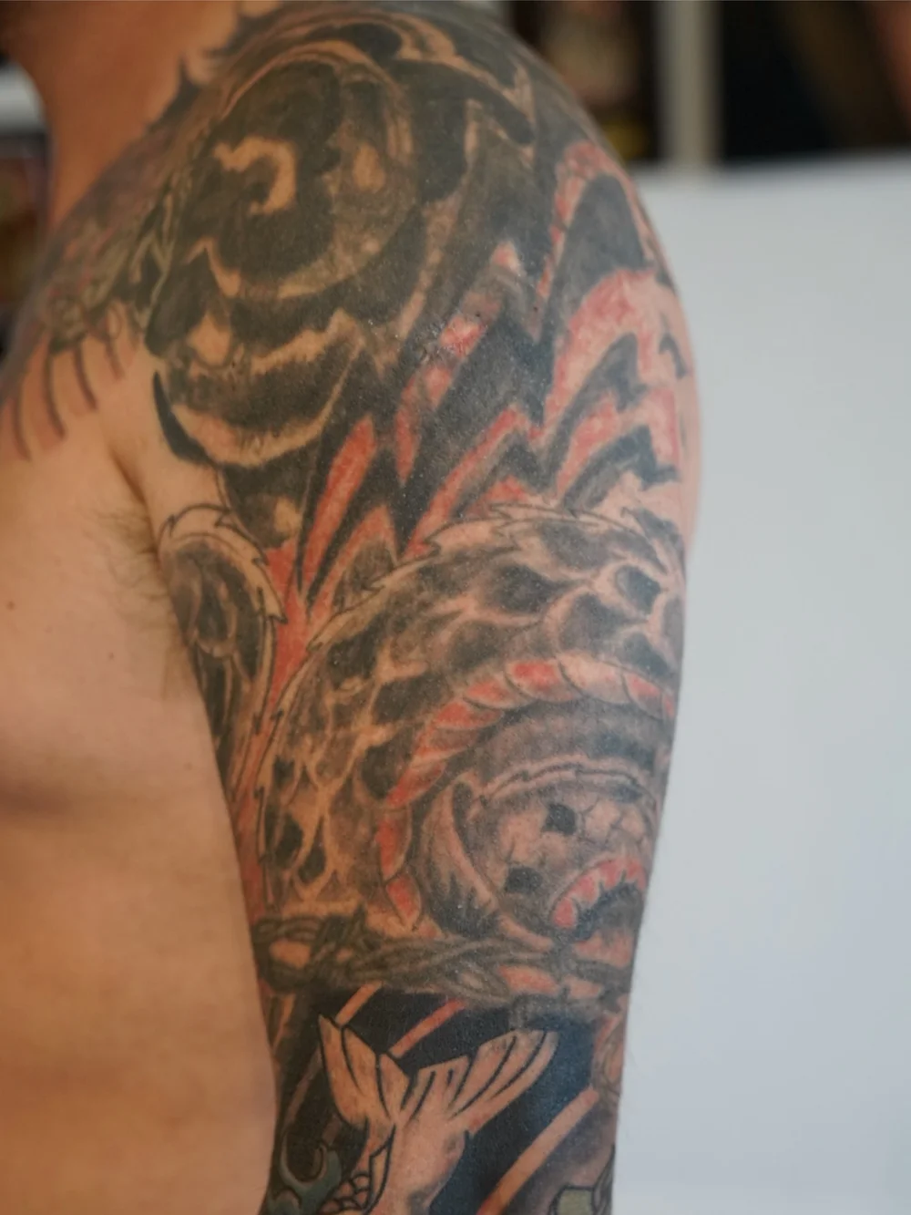 Dark red-and-black upper-arm tattoo before the cover-up