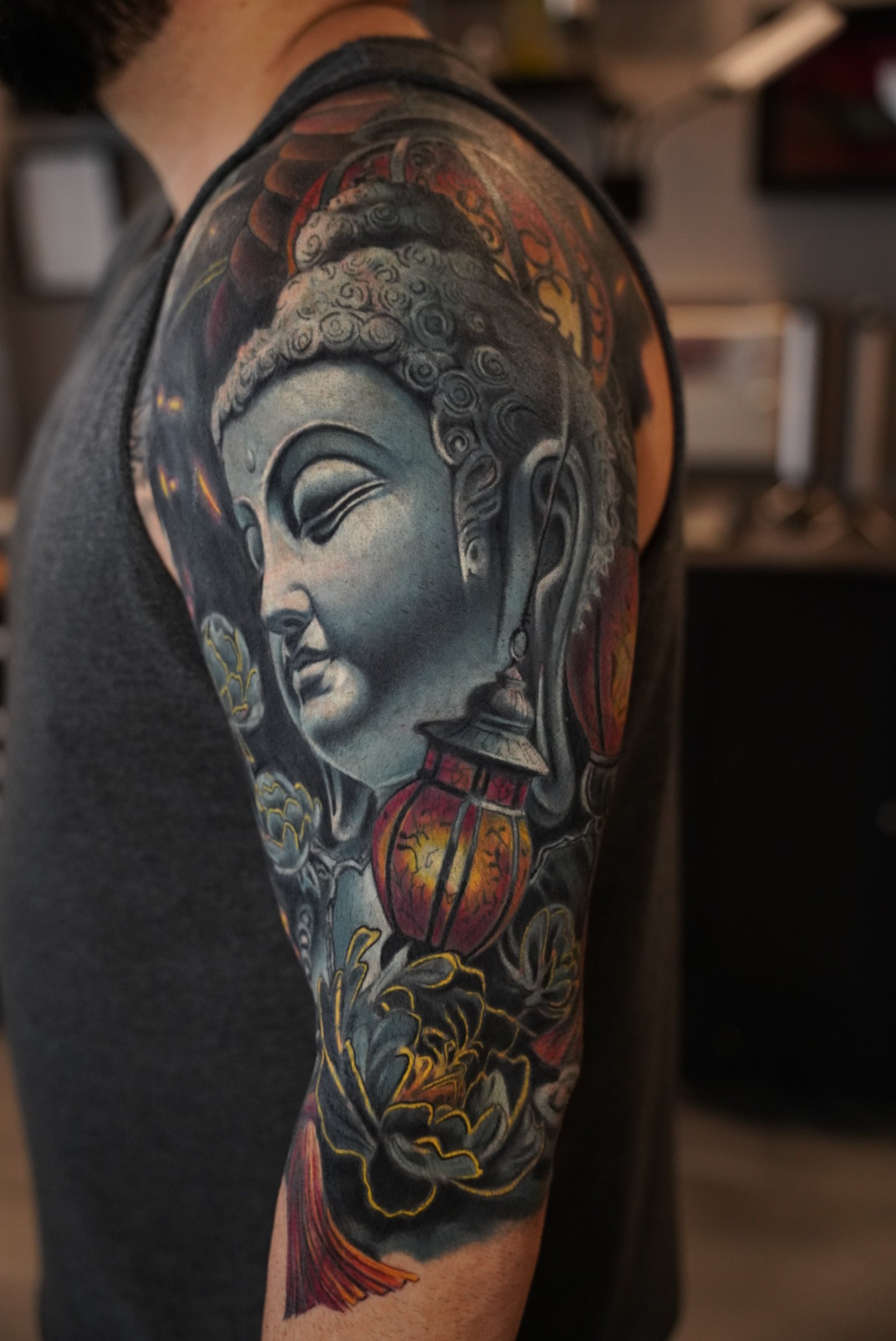 Healed sleeve tattoo with a serene Buddha portrait, warm accent colors, and soft transitions, highlighting balance, spirituality, and refined realism.
