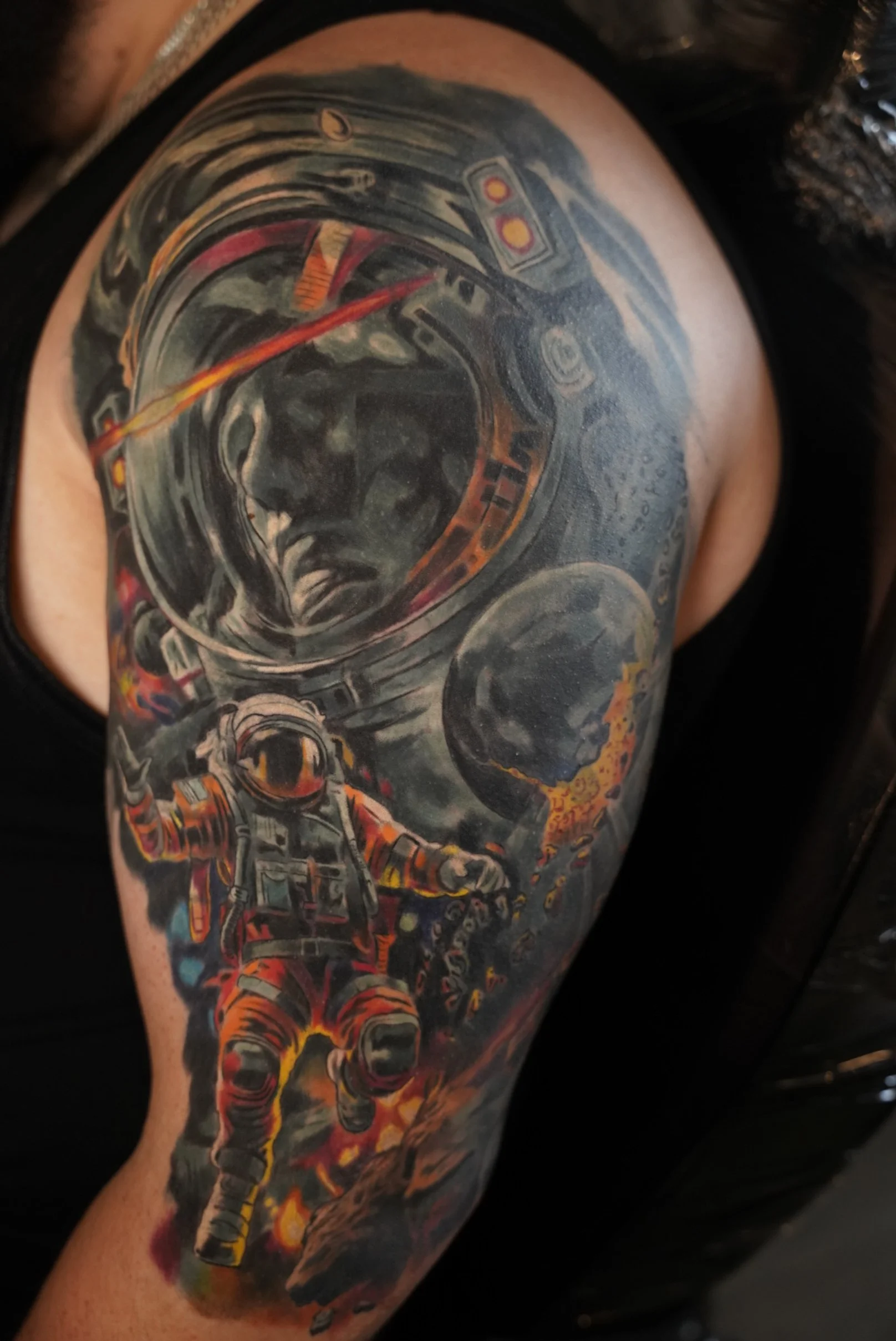 Healed realism tattoo of an astronaut in space, featuring strong contrast, dynamic lighting, and vibrant color accents that bring movement and depth to the piece.