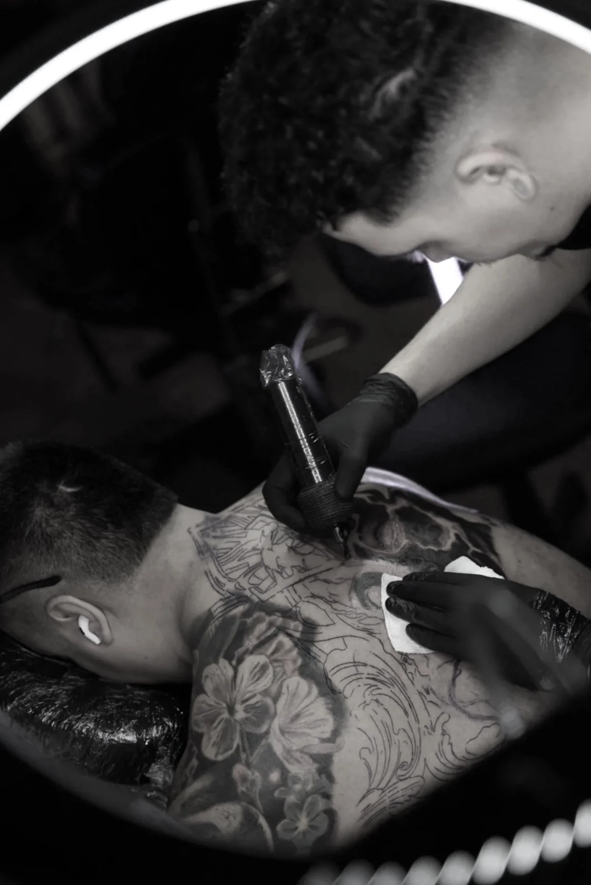 Tattoo artist working on a large-scale color cover up tattoo during an in-progress session.