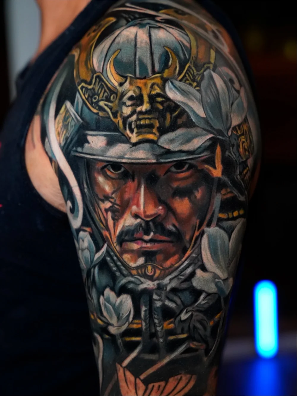 Realistic samurai portrait cover-up on the upper arm with a gold helmet ornament