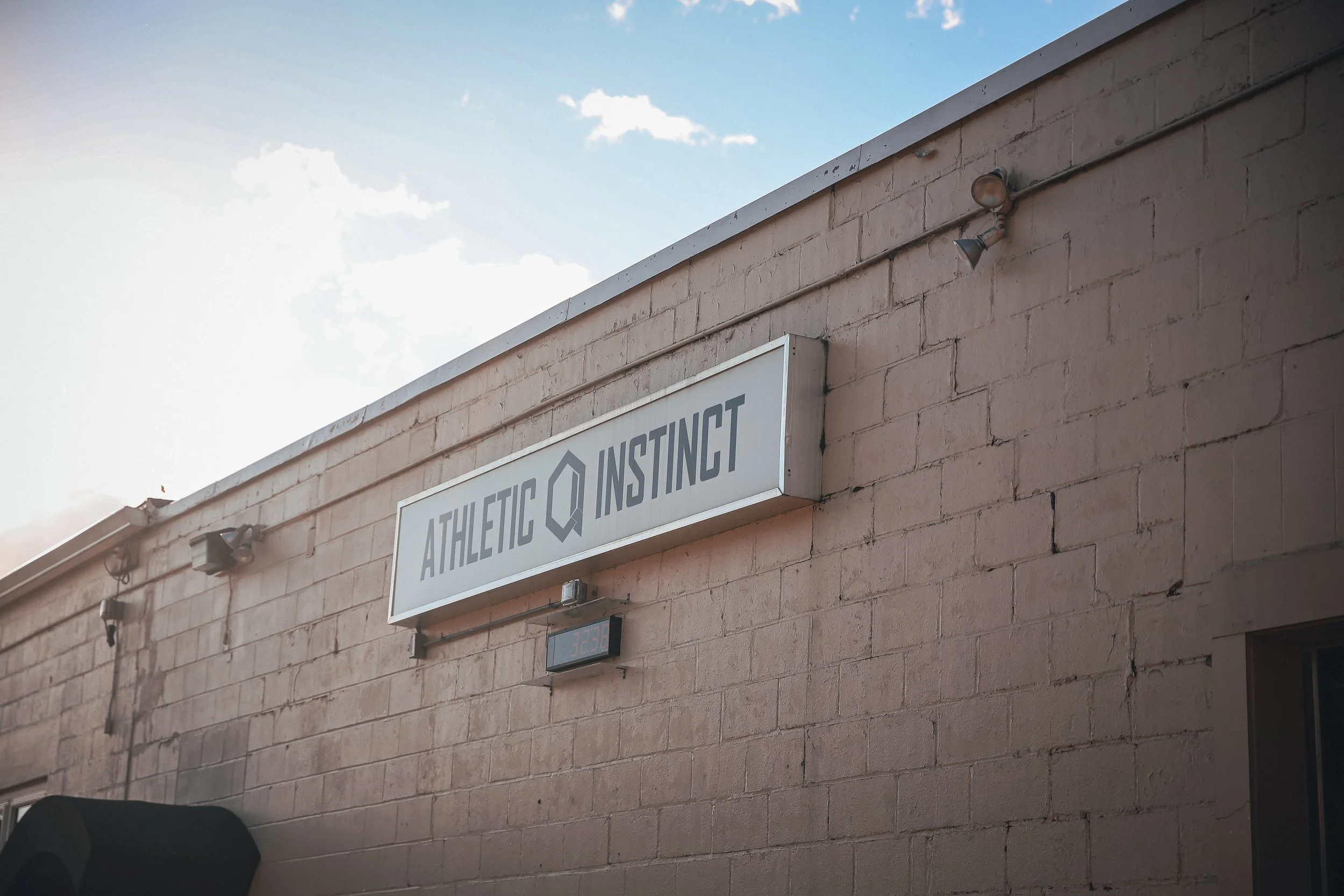 Exterior of a building with a sign that reads 'Athletic Instinct' and a small LED display showing the temperature.