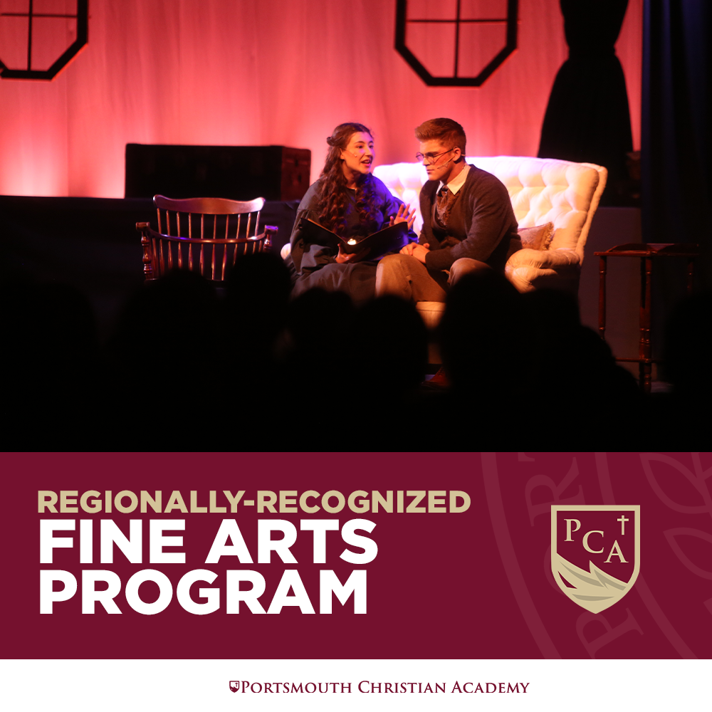 Two actors performing a scene on stage, sitting on a vintage sofa, with a backdrop of red curtains and stage lighting. The scene appears to be part of a theatrical play.