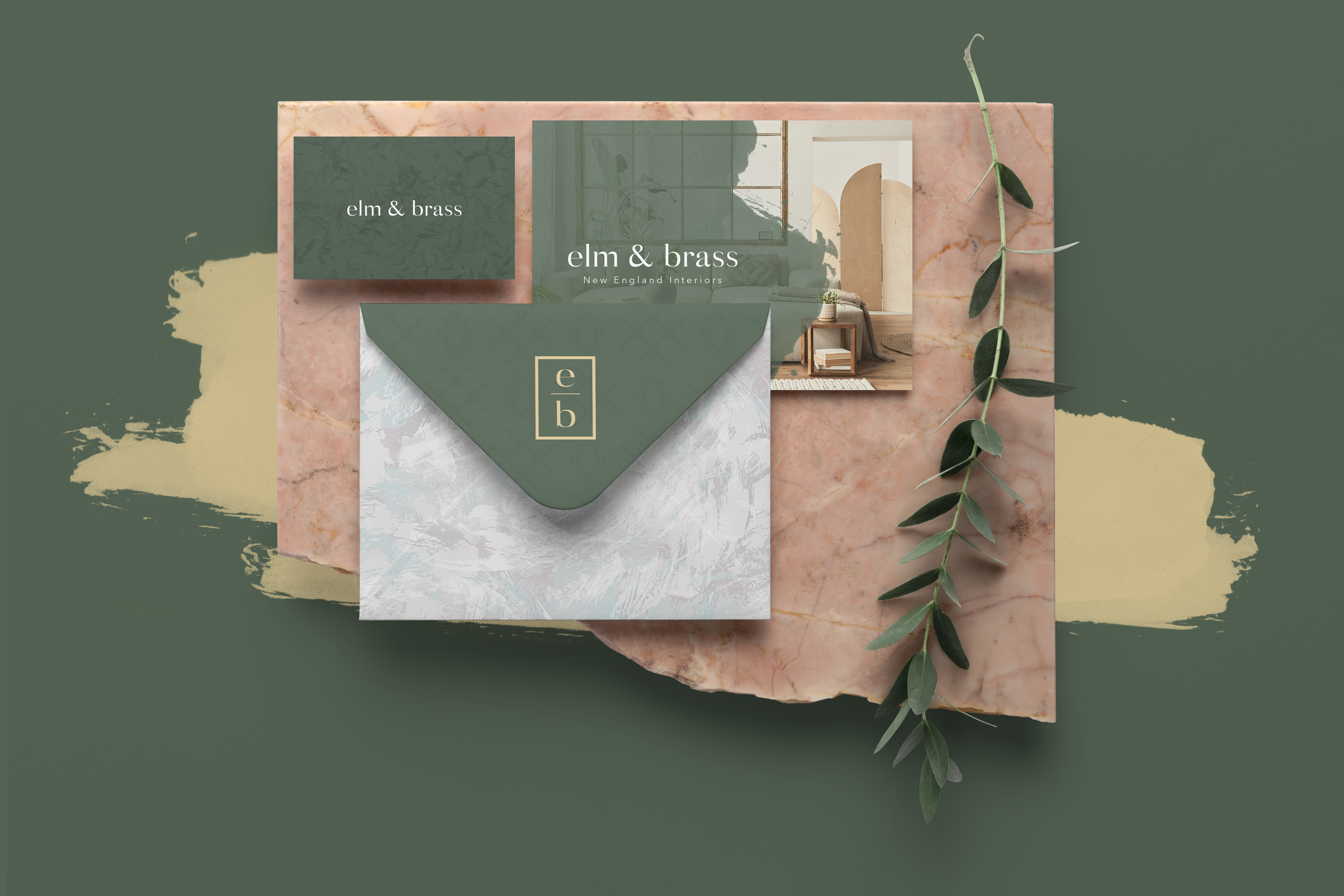 Decorative branding display for 'elm & brass,' featuring a box, printed materials, and a sprig of greenery on a marble and paint background.