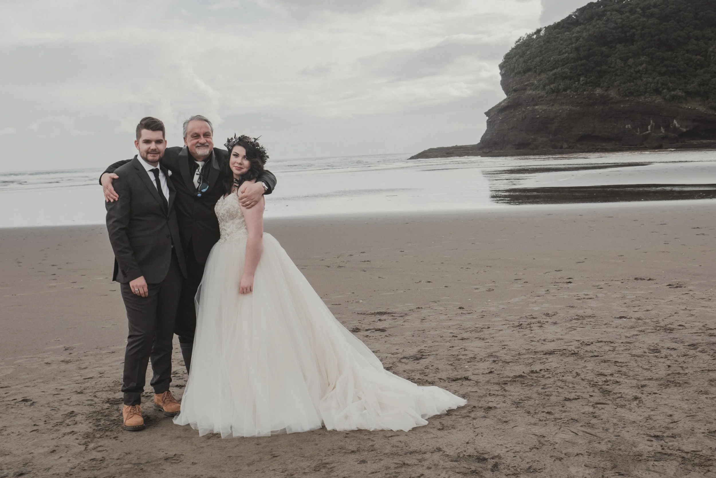 Portrait image of a recently married couple posing with their celebrant.