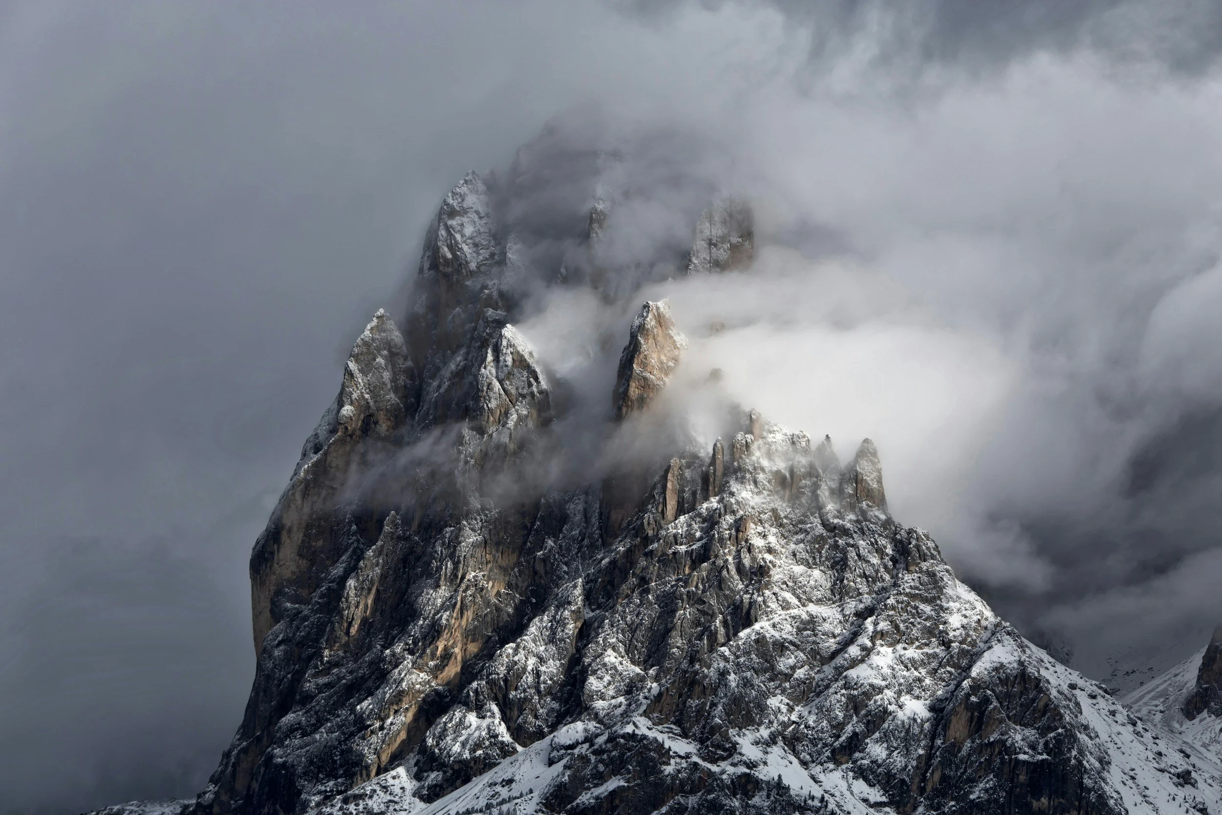 Snow-covered mountain peak surrounded by clouds and mist.