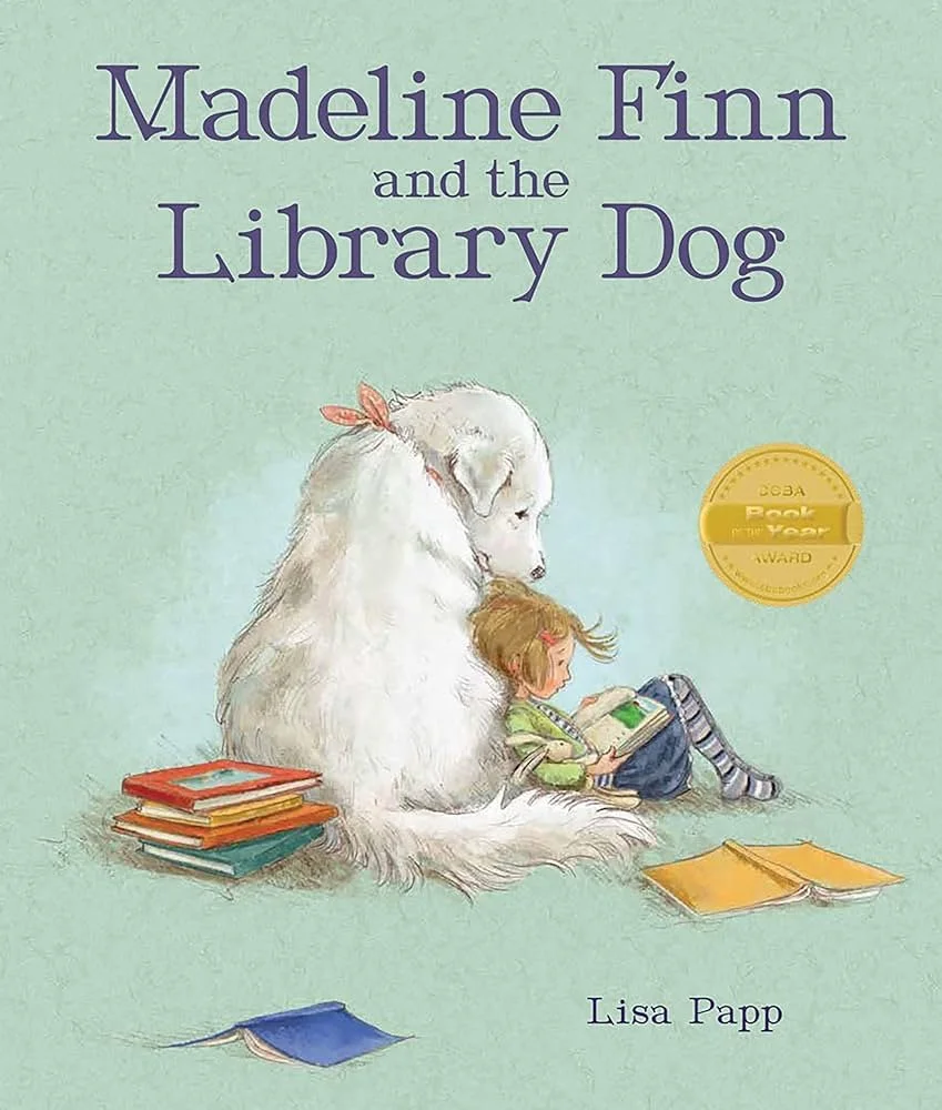 Book cover for 'Madeline Finn and the Library Dog' by Lisa Papp, featuring an illustration of a young girl reading a book while sitting next to a large, fluffy white dog, with several books around them.