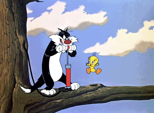 Tom the cat and Tweety Bird sitting on a tree branch with a comic-style sky background, with Tom operating a boxing puncher game.