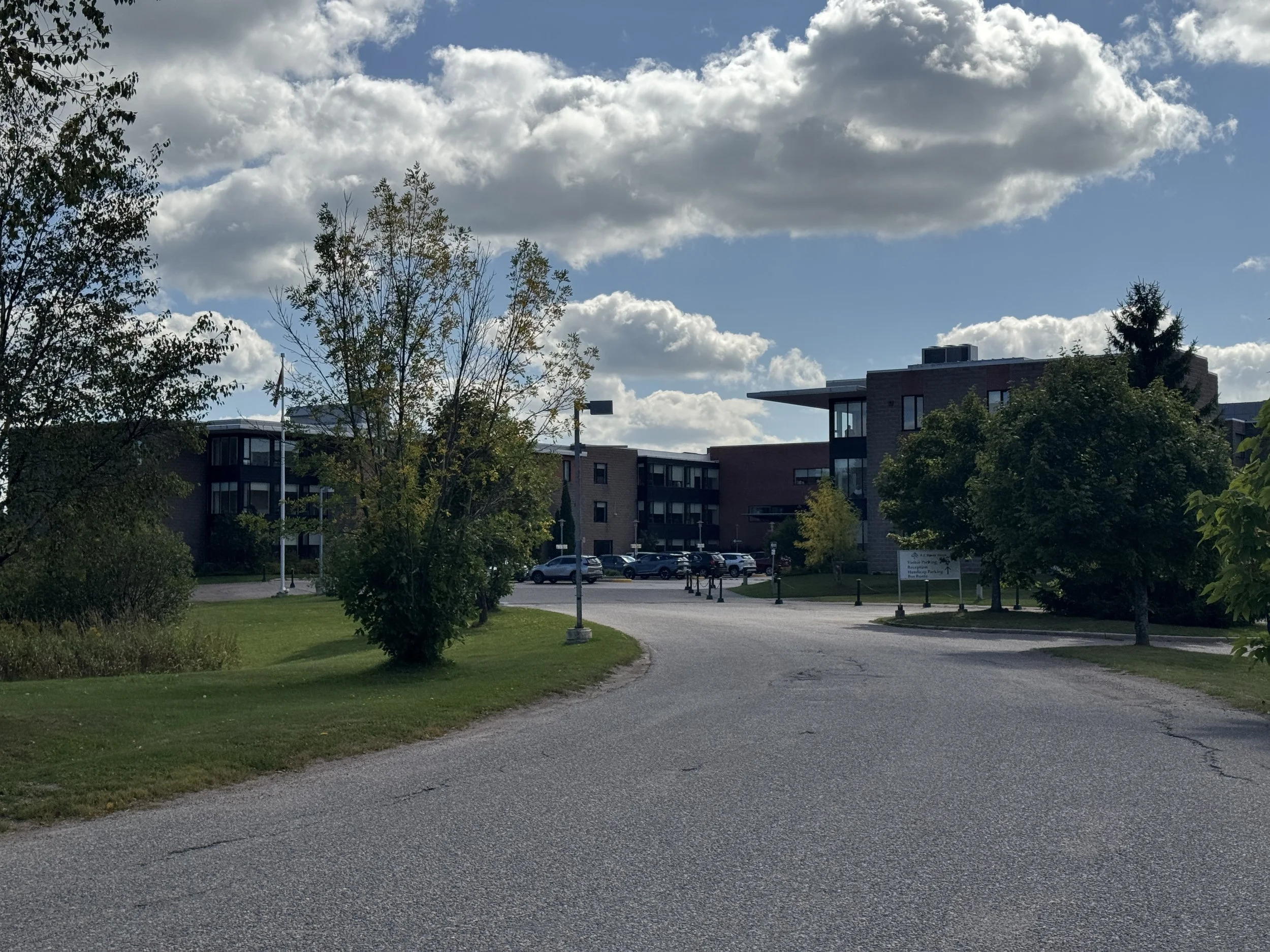 The image shows an apartment complex with a parking lot and grassy area in front.