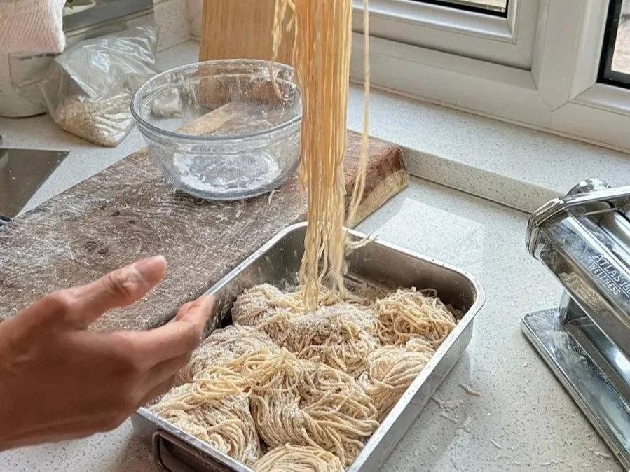 Freshly made noodles being prepared in a kitchen.