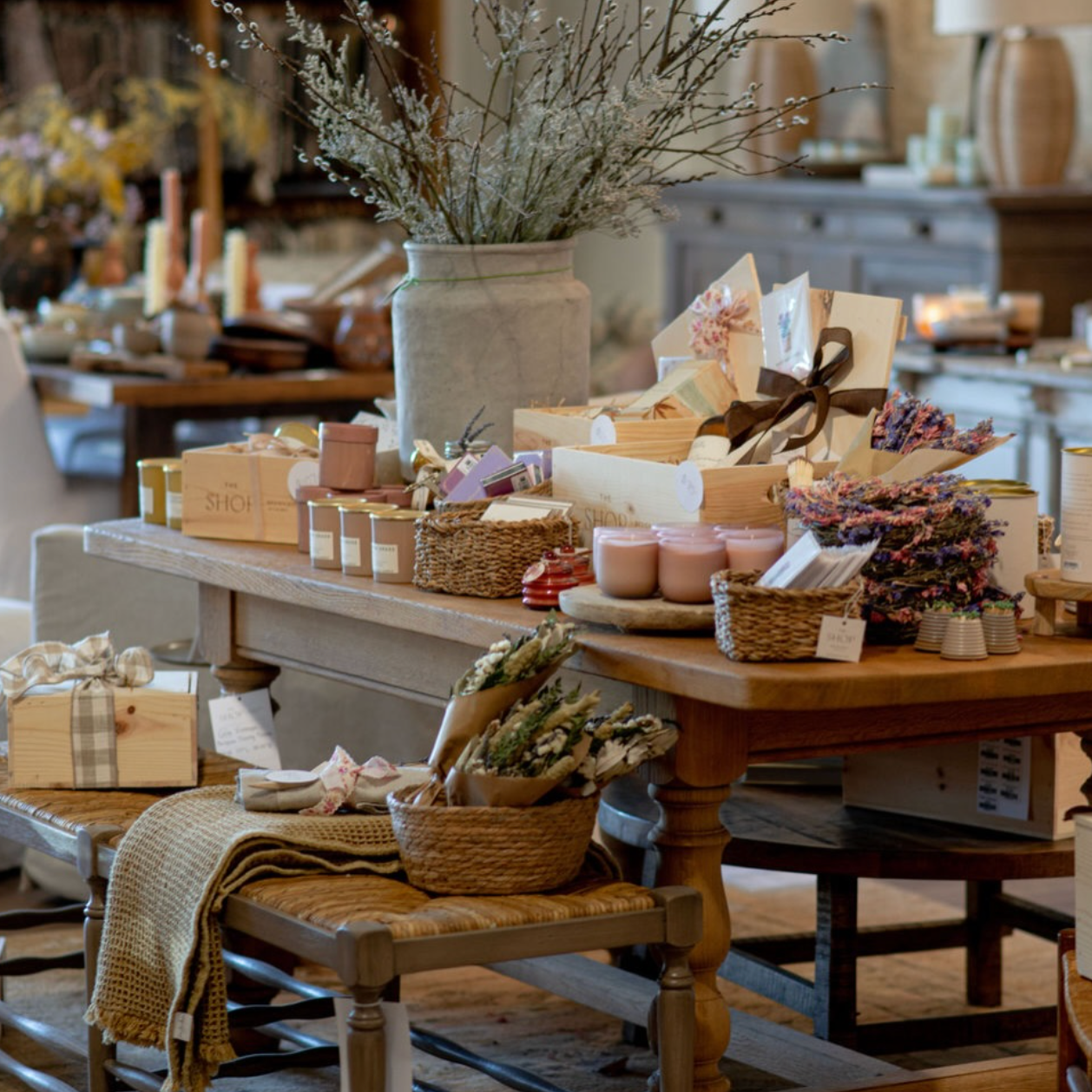 A display table with various gift items, candles, and decorative flowers in a gift shop setting.