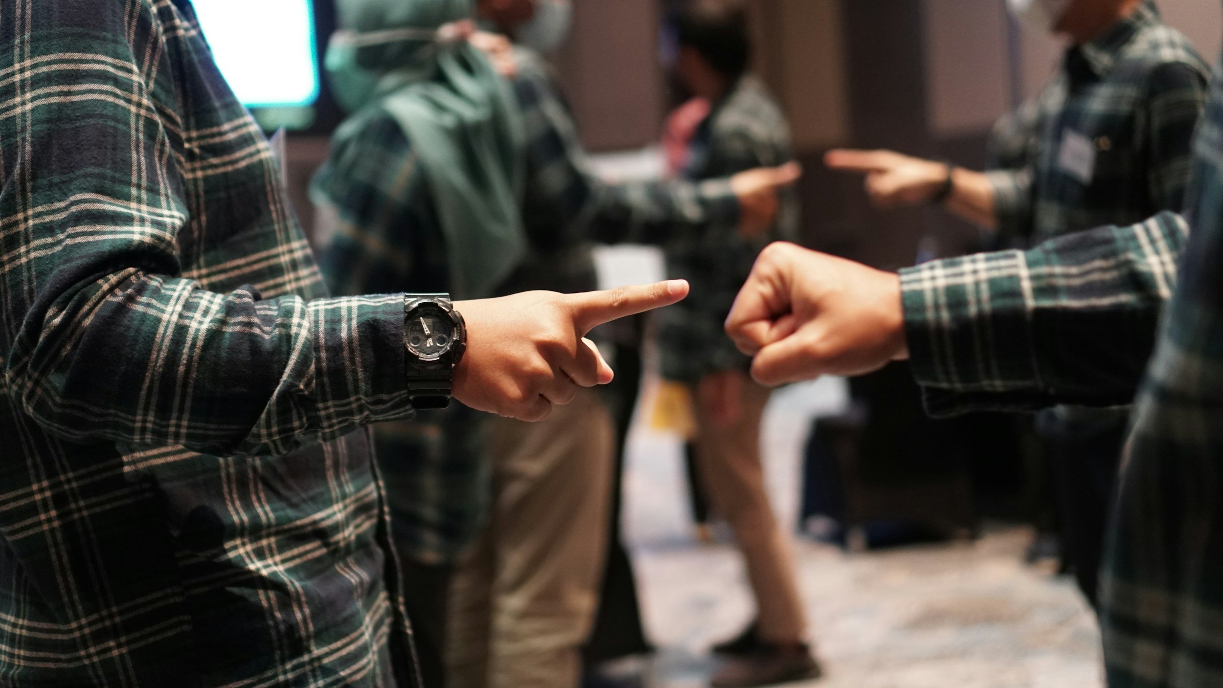 Two people exchanging contact information at a networking event, with others in the background.