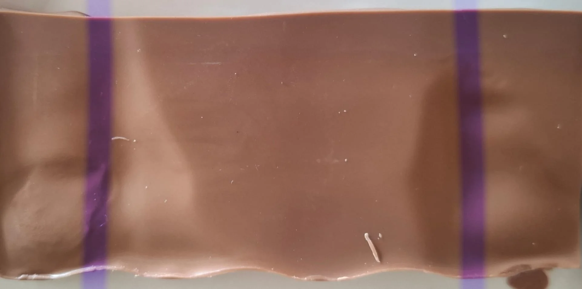 Close-up of a partially unwrapped chocolate bar with purple stripes on the wrapper.
