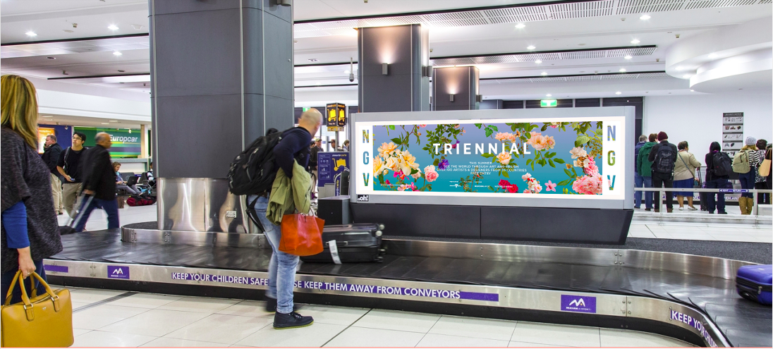 NGV Triennial exhibition banner by Fallen Fruit (David Allen Burns and Austin Young) displayed above the baggage claim at Melbourne Airport, Australia.