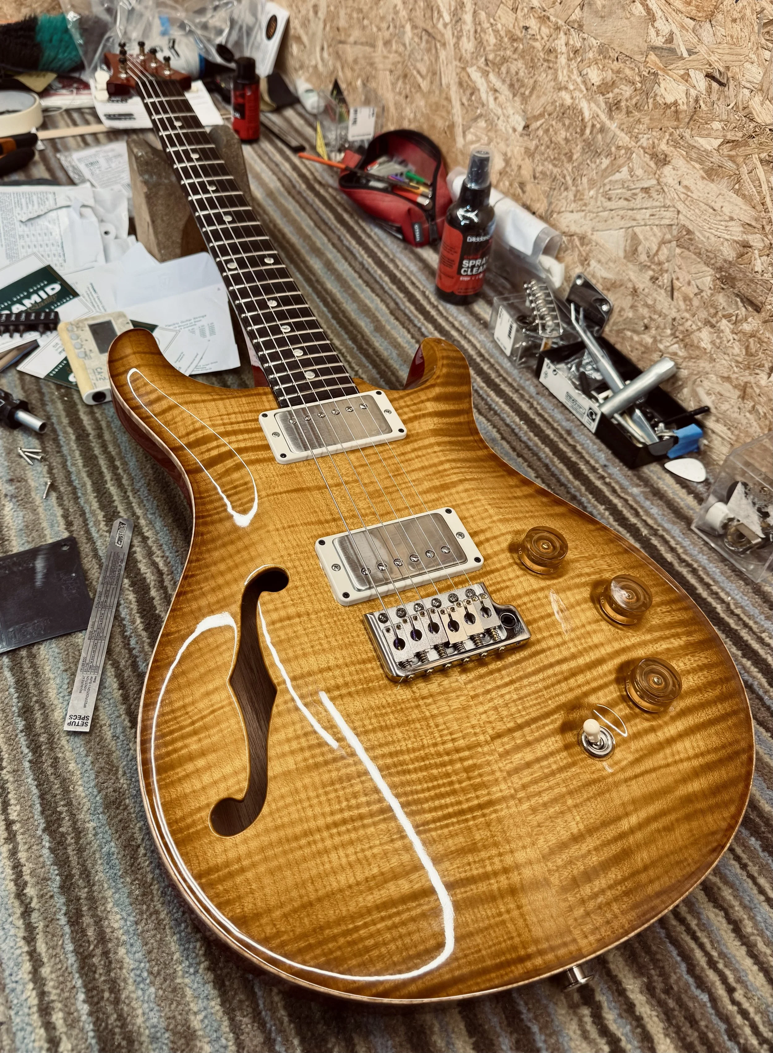 Electric guitar with a rich, wood grain finish on a cluttered workbench.