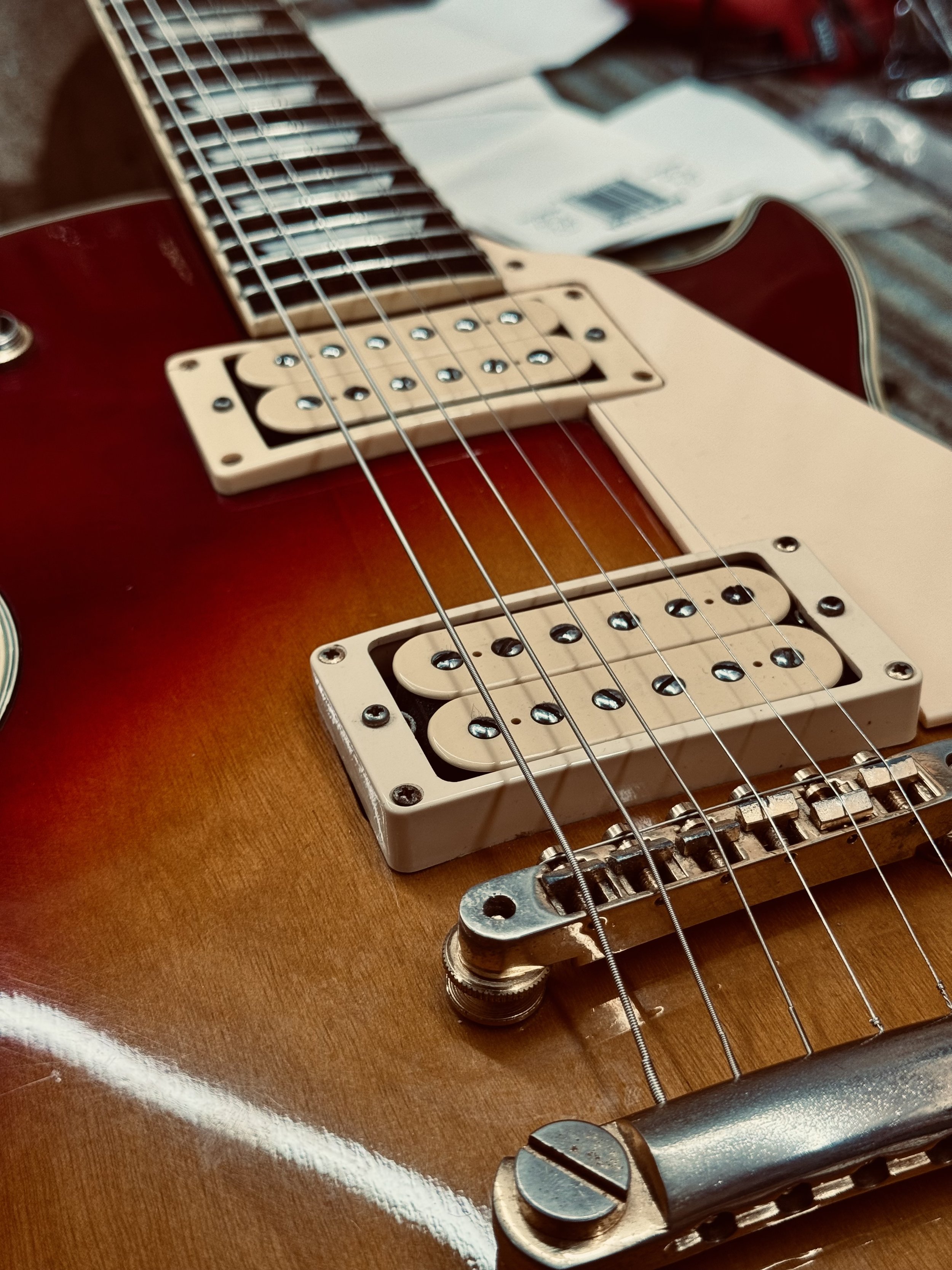 Close-up of an electric guitar after a repair with a sunburst finish, showing the pickups, strings, bridge, and part of the fretboard.