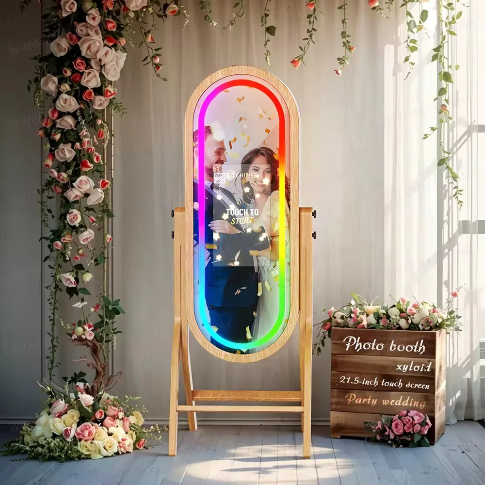 A couple taking a photo in a colorful, illuminated photo booth surrounded by flowers and greenery, with a sign indicating the booth is for a party wedding.