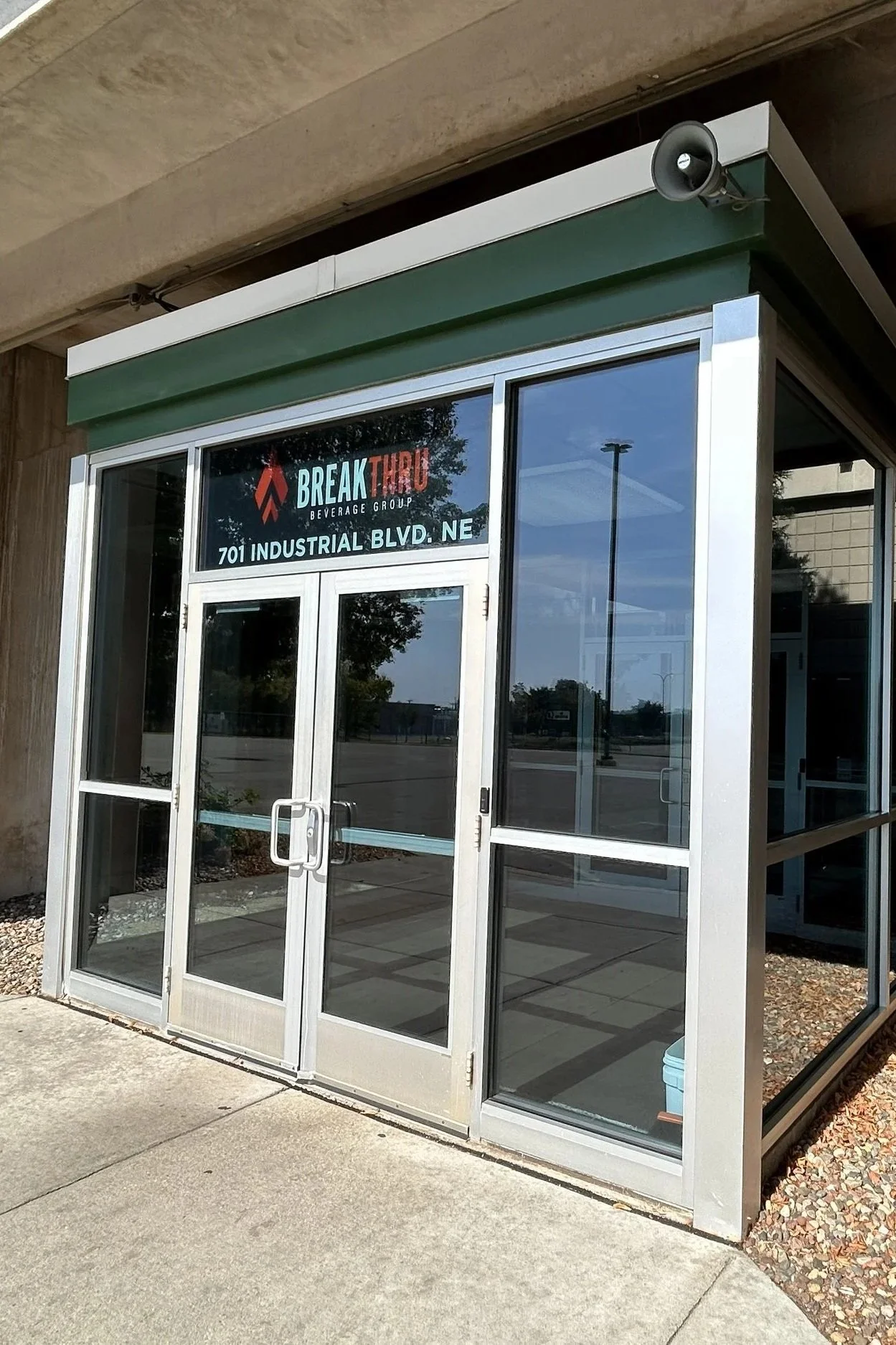 Exterior view of a glass storefront with a sign for 'Break Thru Beverage Group' located at 701 Industrial Blvd NE.