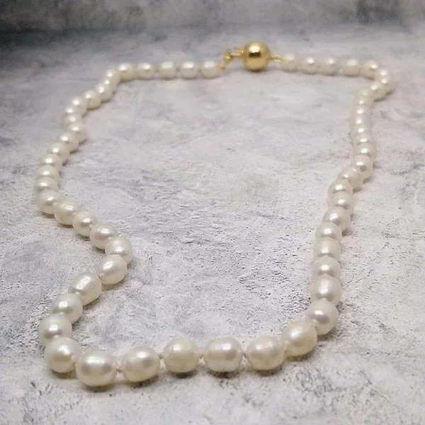 Strand of champagne pearls on knotted silk with gold spherical clasp