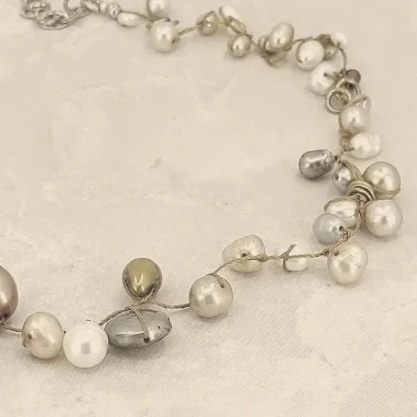 section of Fresh Water Pearl necklace; pearls offset-strung, about 4 per inch along the 4 inch visible section.  Pearls are various neutral colors: silver, champagne, white, etc