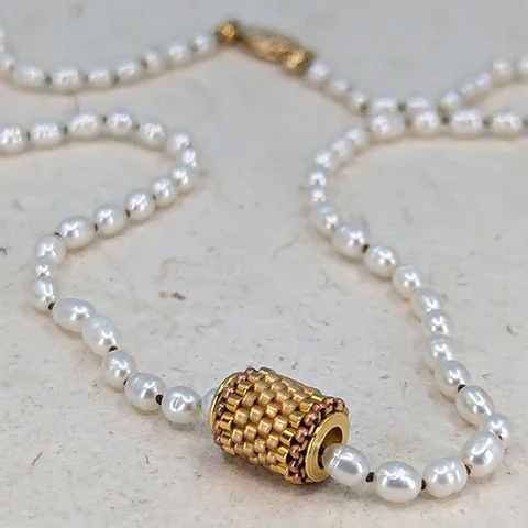 Pearl necklace with a gold Japanese glass floating bead, and a gold clasp.