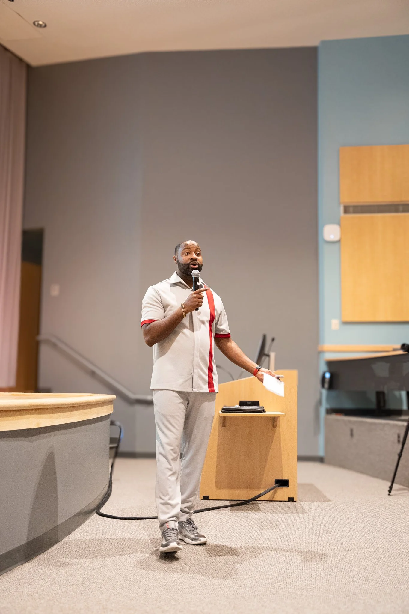 Man speaking into a microphone during a presentation in a conference room.