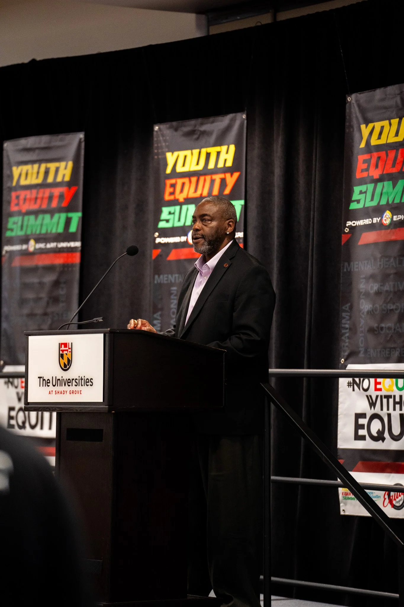 Man speaking at podium during Youth Equity Summit at The Universities at Shady Grove.