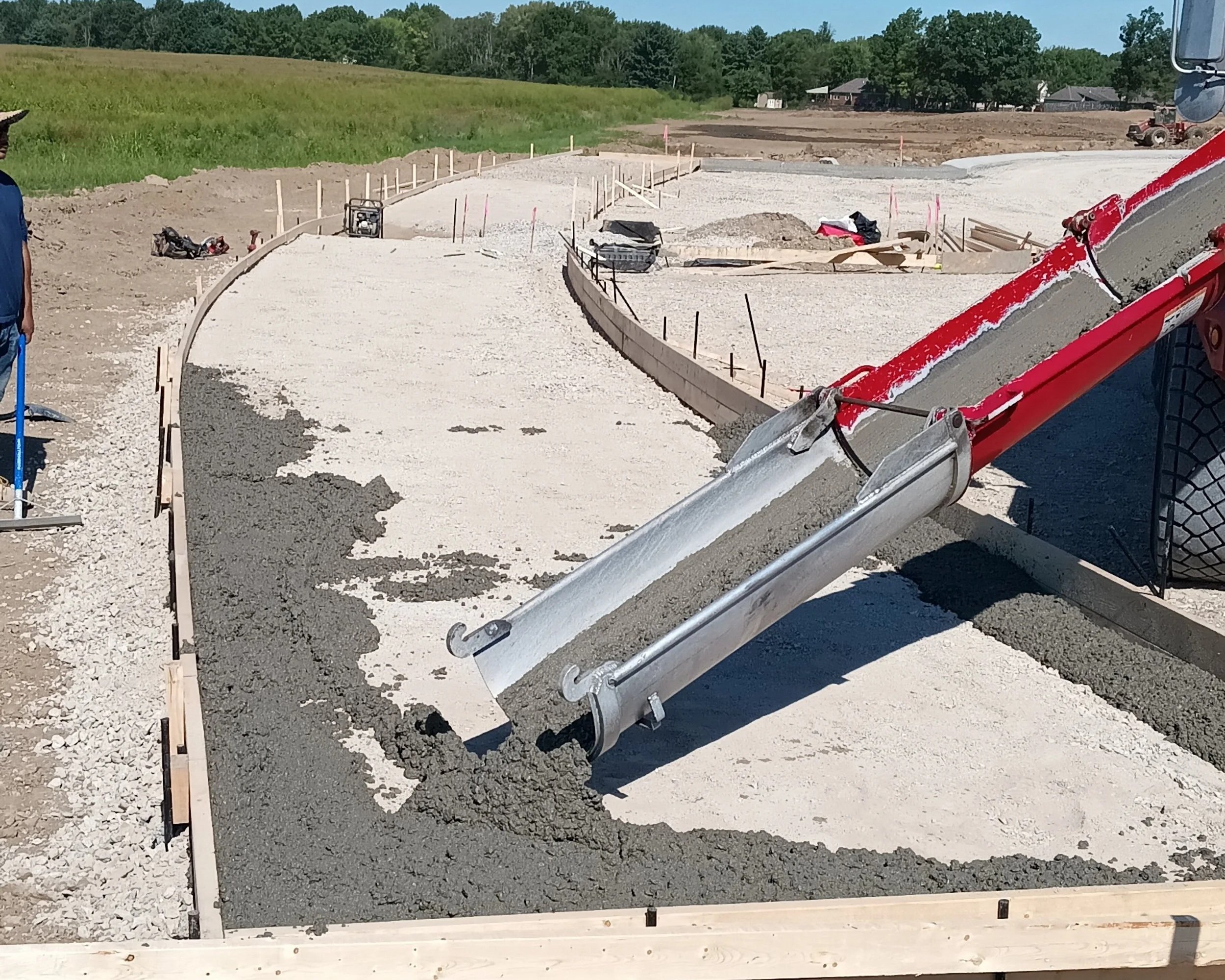A construction site where concrete is being poured into a curved foundation for a building or structure.