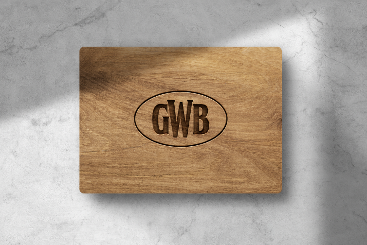 Wooden cutting board with the initials "GWB" engraved inside an oval.
