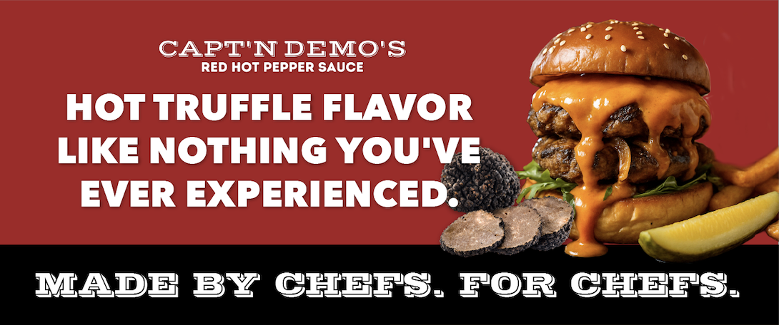 A burger with cheese, lettuce, and a sesame seed bun, served with lemon wedges and black truffle slices on the side, on a red background promoting a spicy burger with hot truffle flavor.
