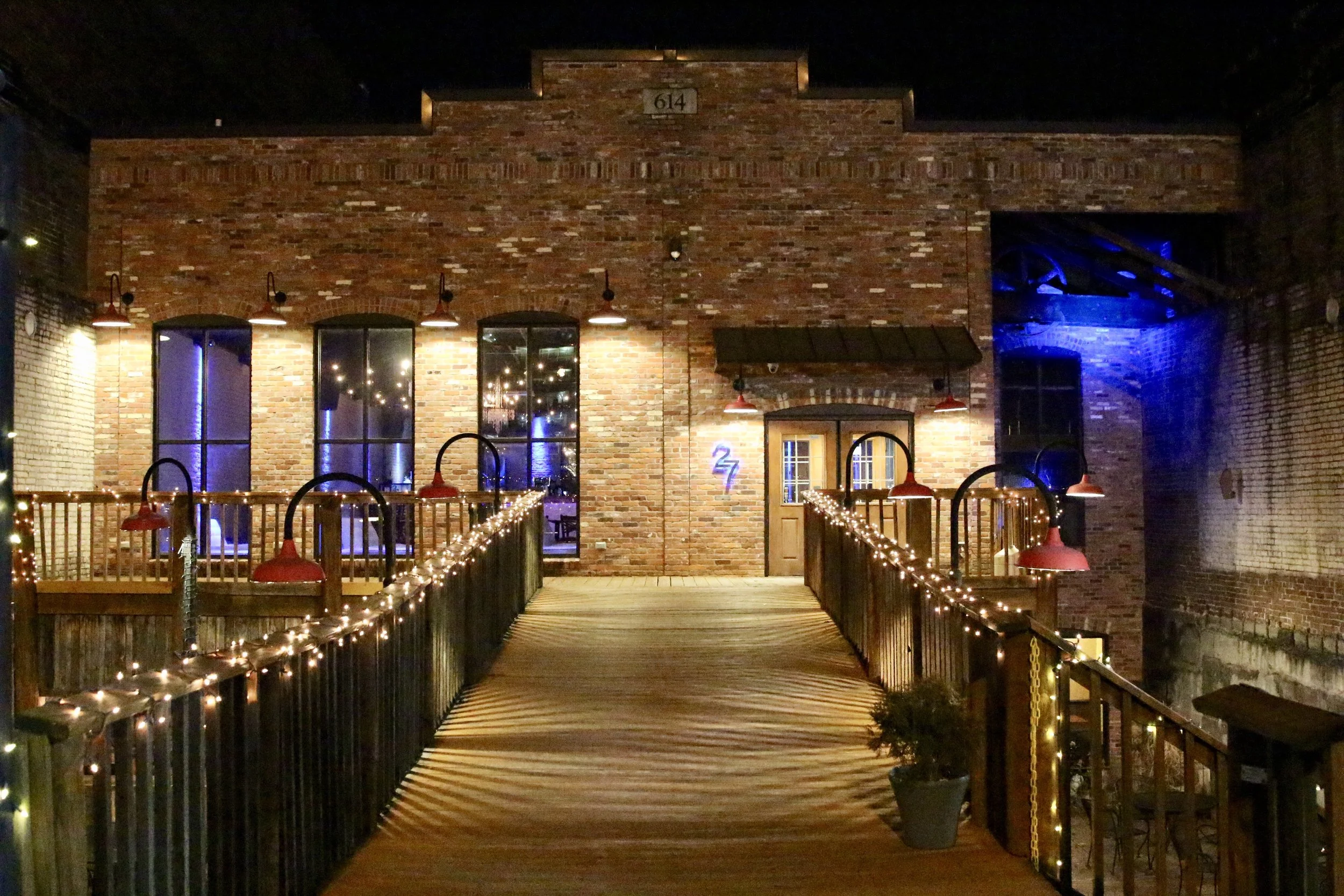 Brick building with pathway and string lights at night.