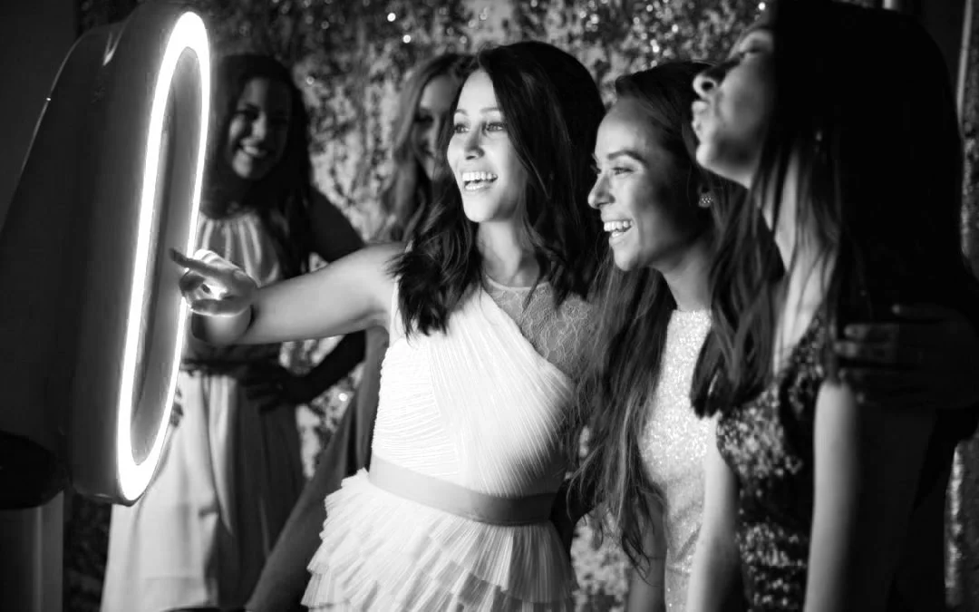 Group of women smiling and interacting with a photo booth at a wedding at Twenty Seven in the River Market in Little Rock