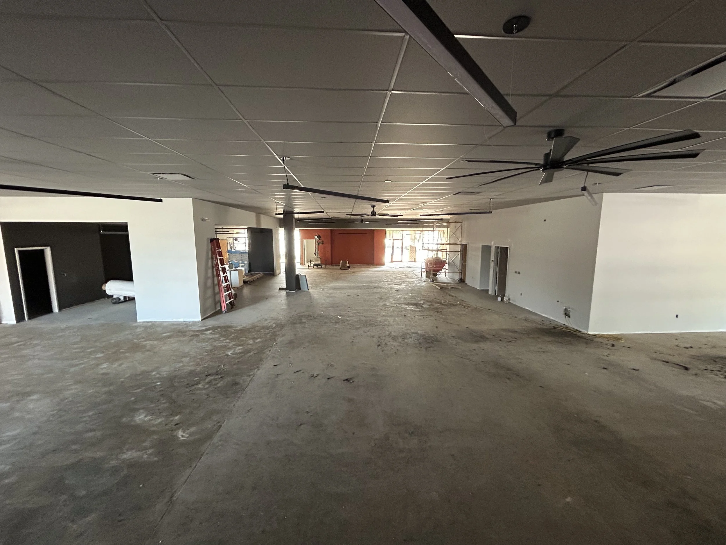 Crucible Fit gym interior during construction, with exposed ceiling components and unfinished flooring.