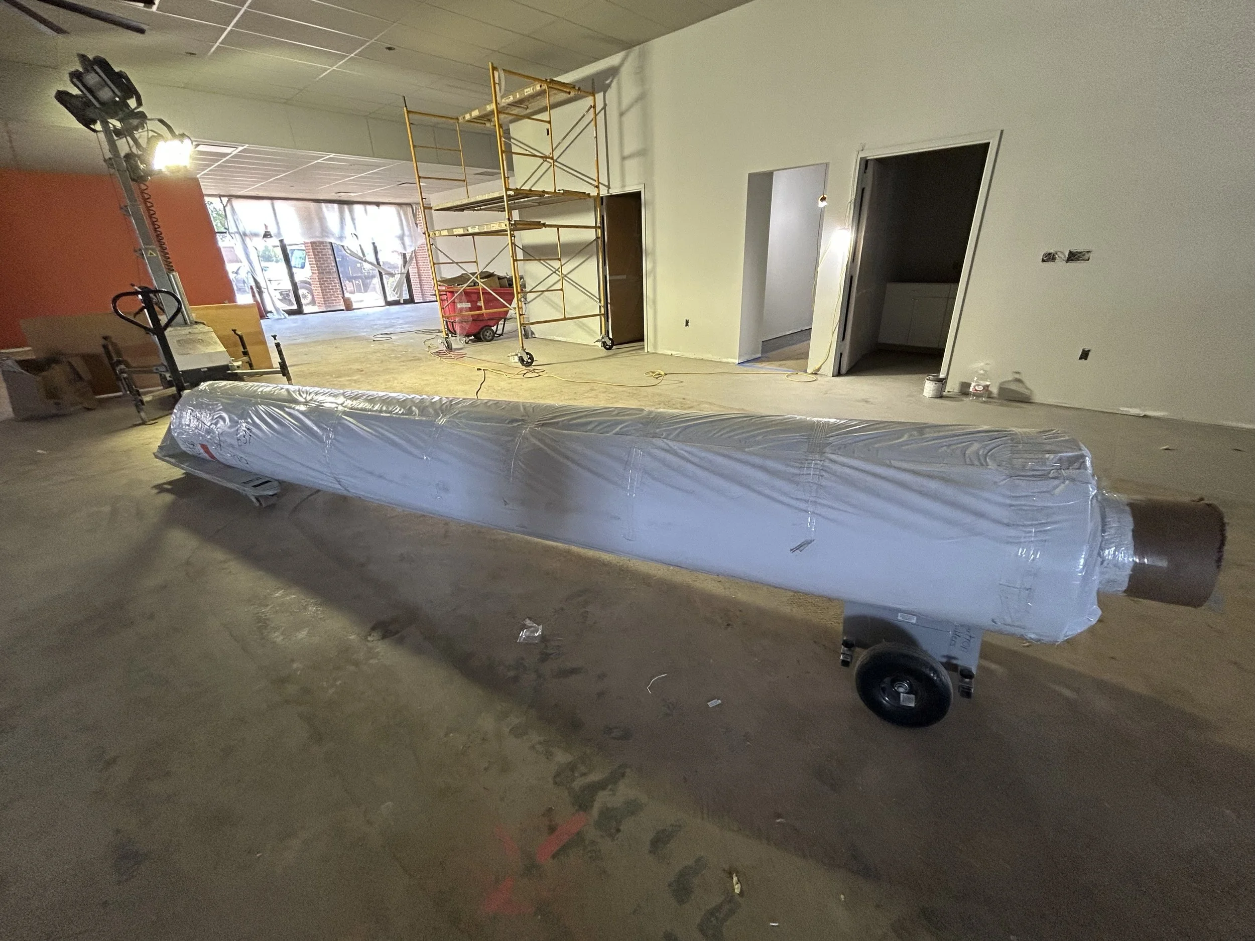 Crucible Fit interior during buildout, with floor preparation underway and construction materials on site.