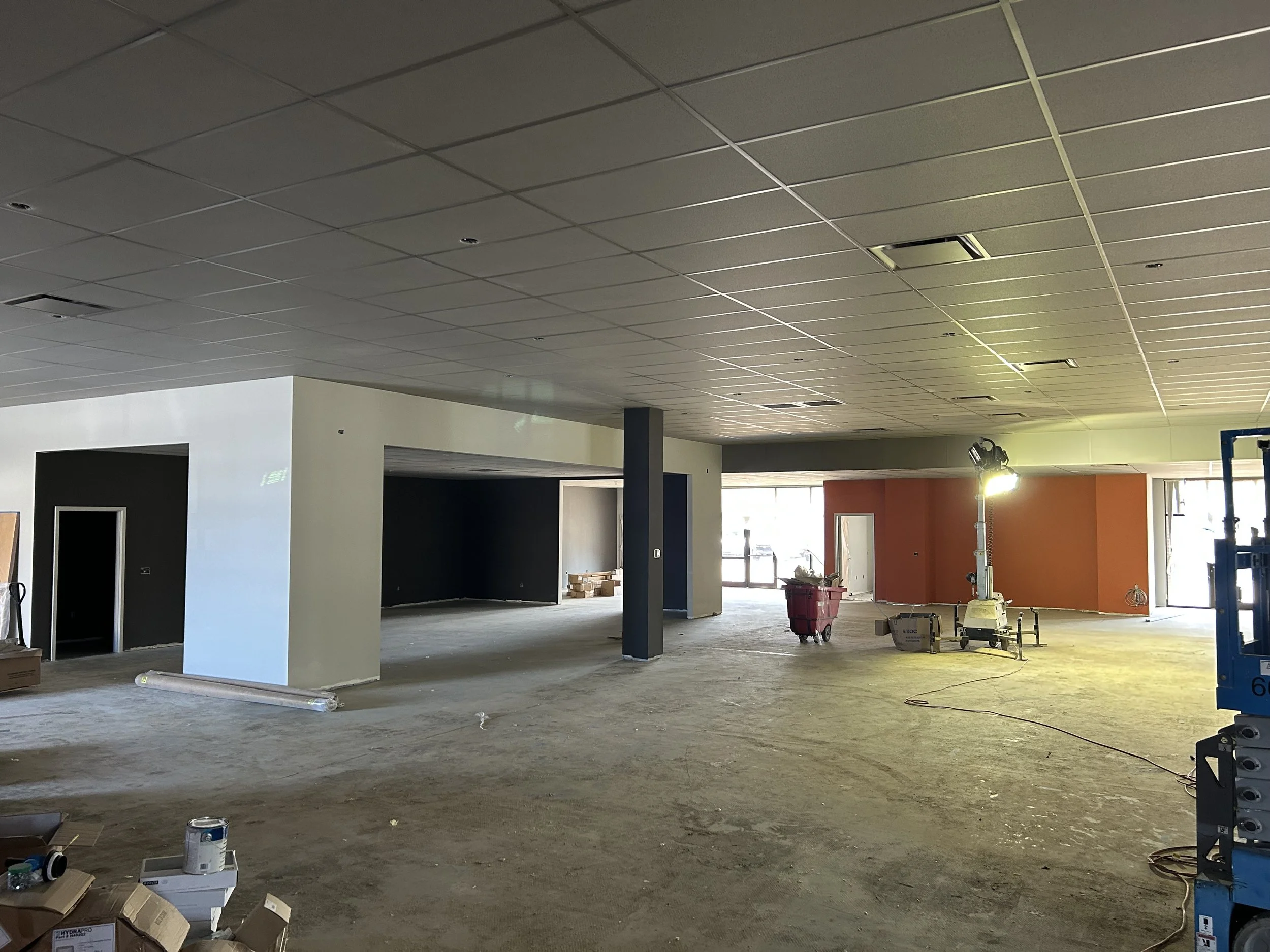 Crucible Fit gym under construction, with partially installed ceiling tiles and orange accent walls.