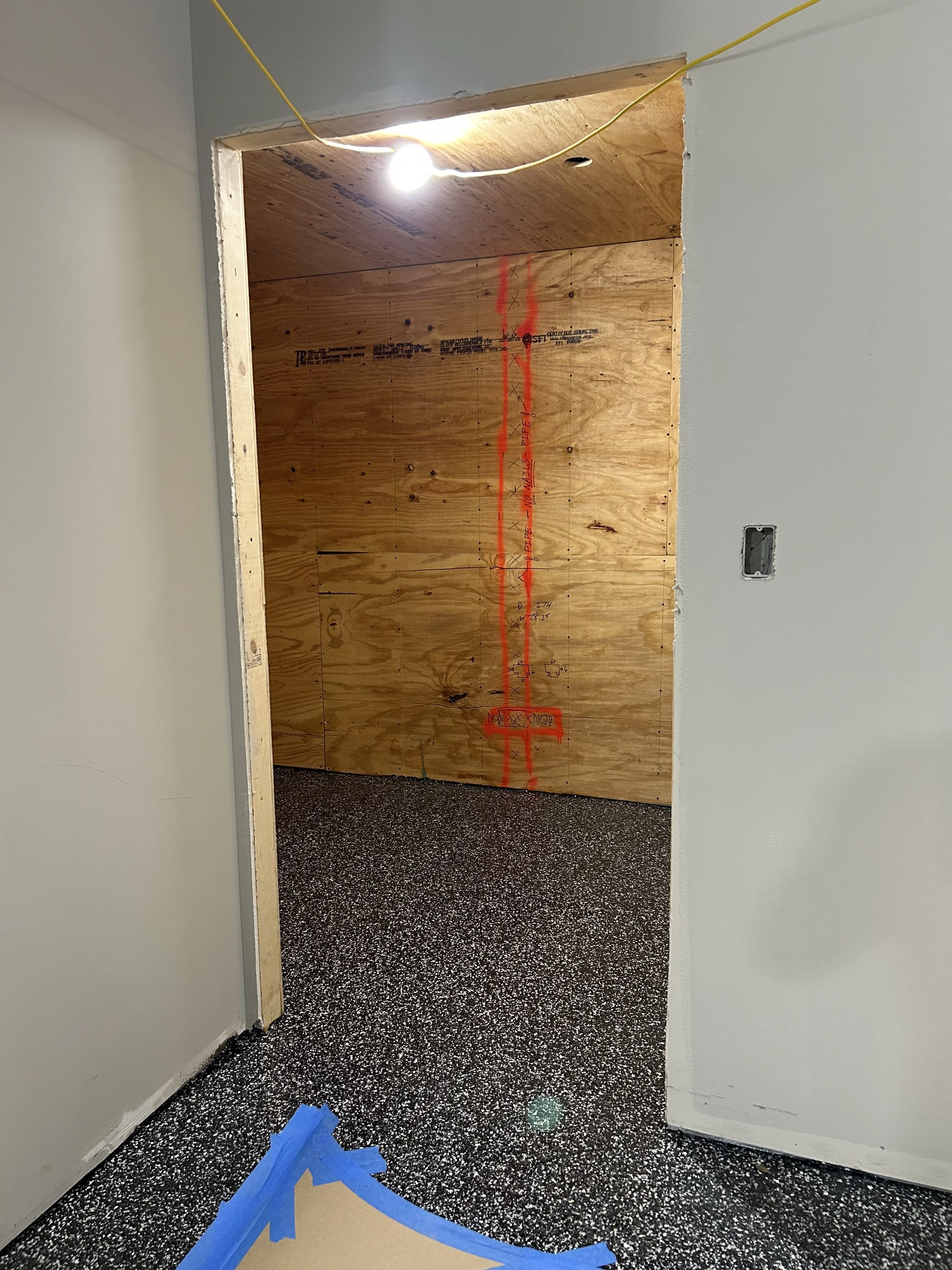 Crucible Fit doorway during construction, with unfinished drywall and flooring installation in progress.
